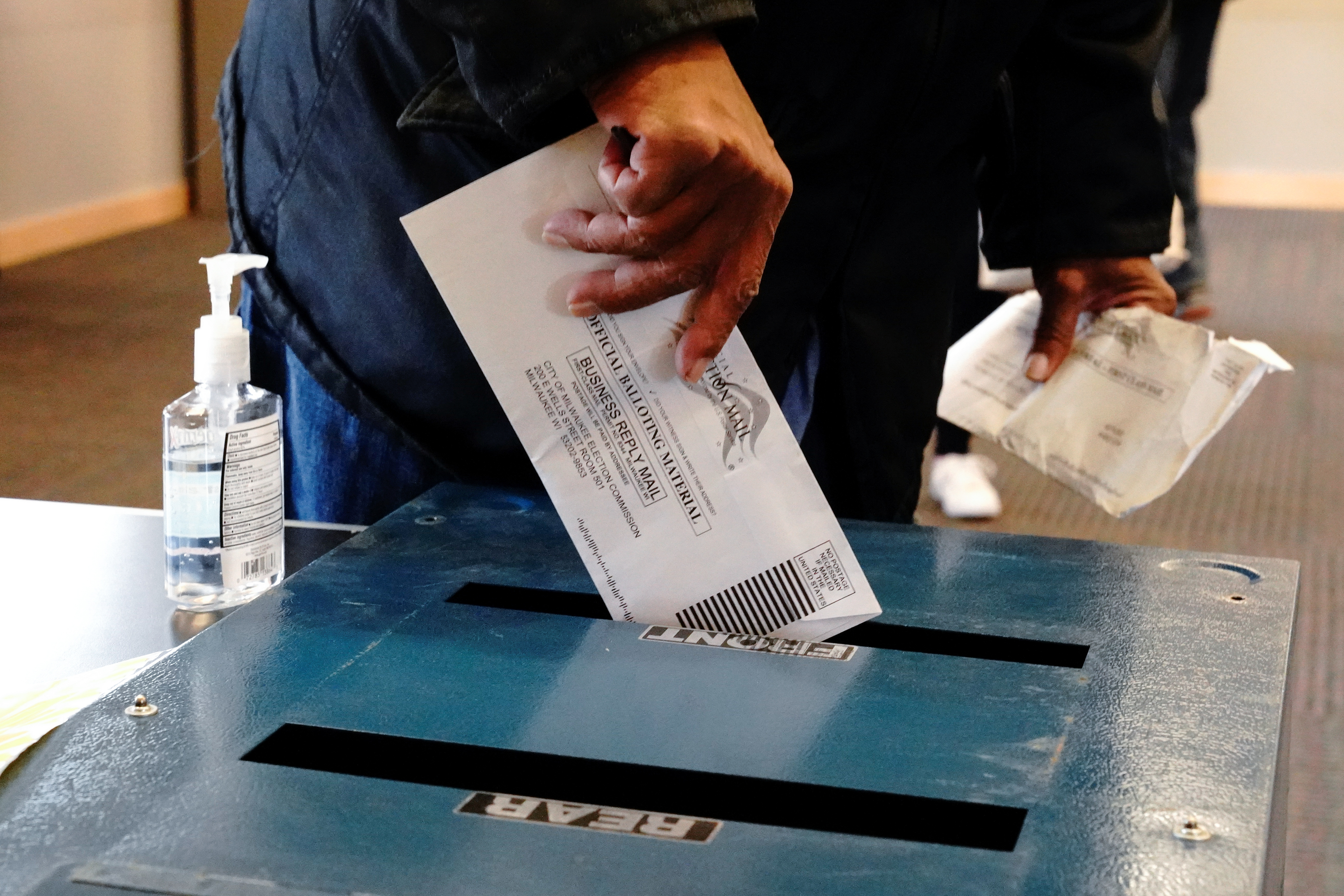 A voter casts his ballot next to a bottle of hand sanitizer at the Milwaukee Public Library’s Washington Park location in Milwaukee, on the first day of in-person voting in Wisconsin, Oct. 20, 2020.