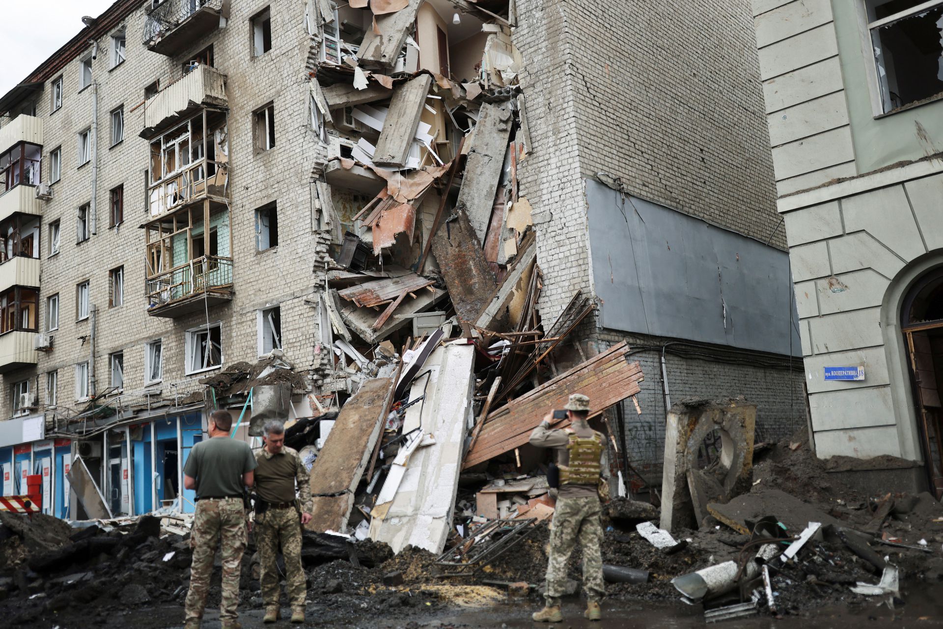 Ukrainian servicemen stand in front of Valentina Popovichuk's flat, where she was rescued after Russian shelling in a military strike, as Russia's invasion of Ukraine continues, in Kharkiv, Ukraine, July 11, 2022.