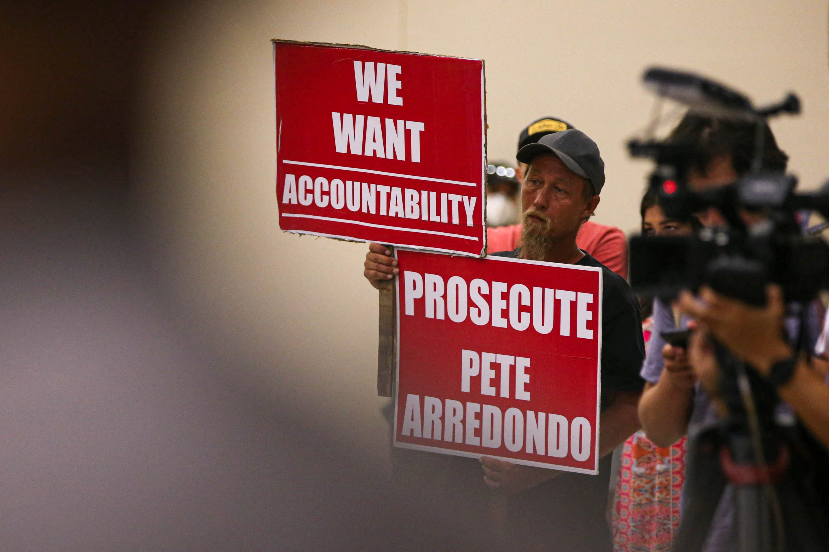 Michael Brown, an Uvalde community member who has a child that was enrolled at Robb Elementary, holds signs calling for police accountability during a hearing by a Texas House Investigative Committee at the SSGT Willie de Leon Civic Center in Uvlade, Texas, July 17, 2022.