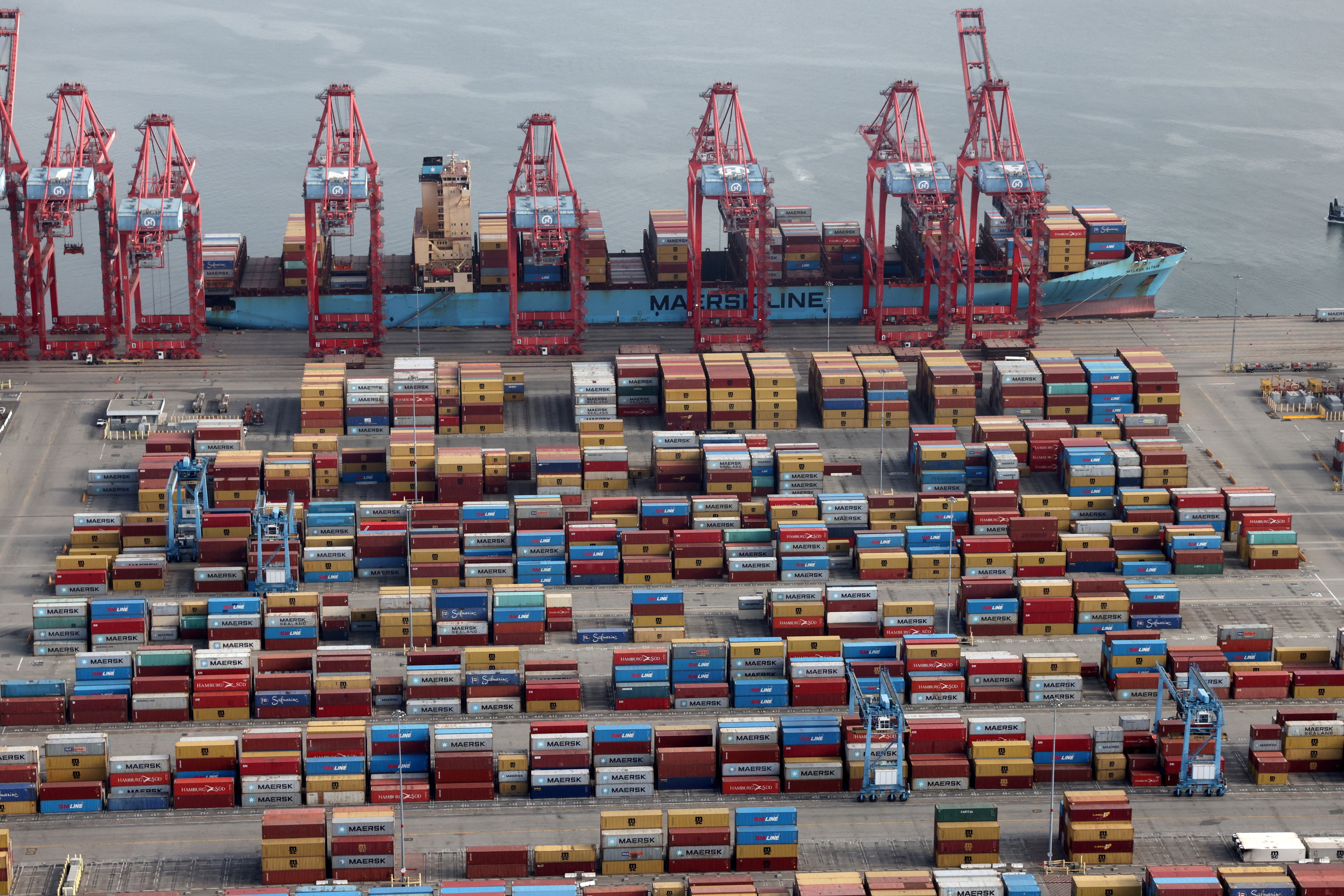 Shipping containers are unloaded from a ship at a container terminal at the Port of Long Beach-Port of Los Angeles complex, in Los Angeles, California, April 7, 2021.