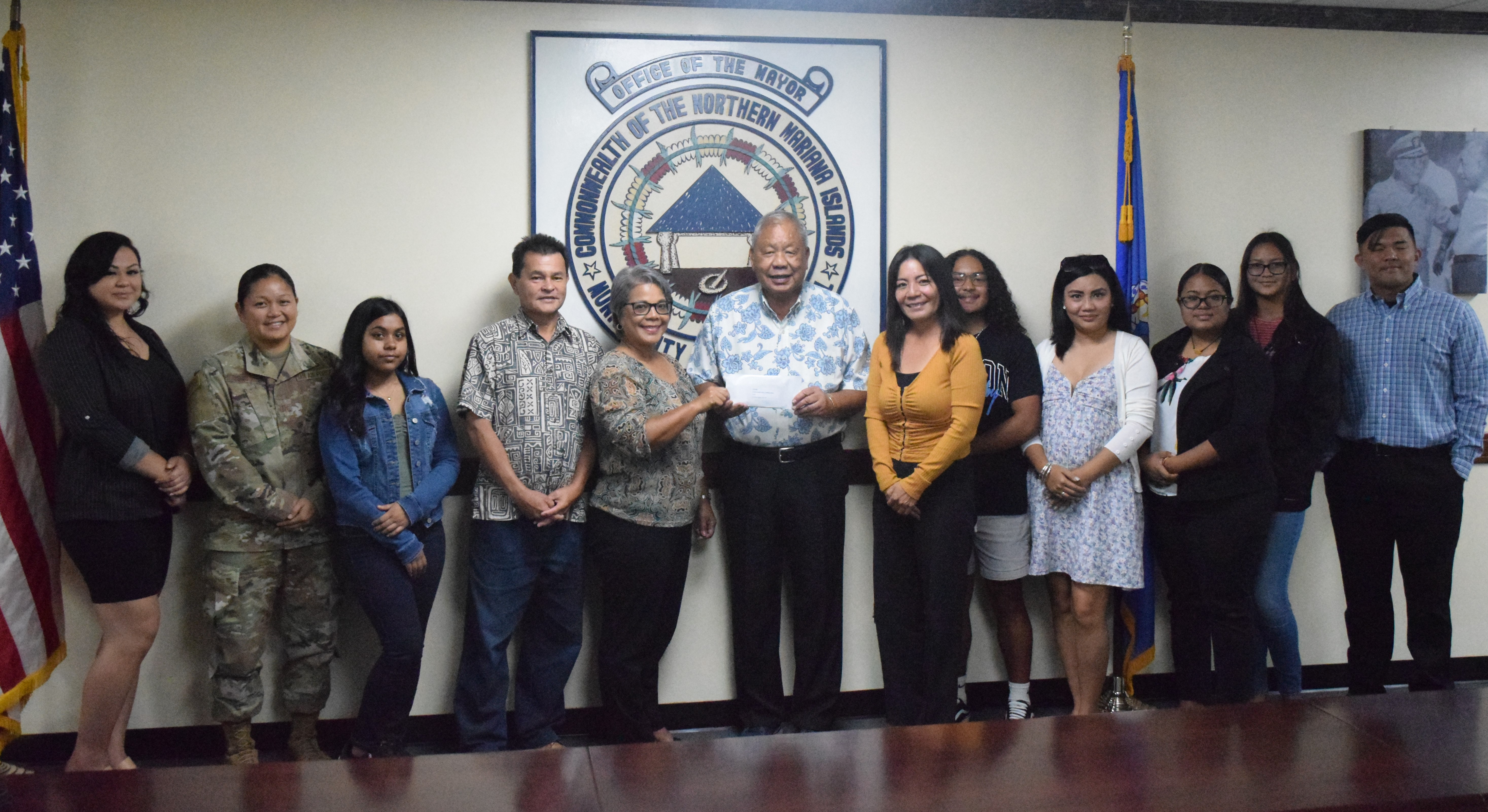 Saipan Mayor David M. Apatang hands a check for $5,000 to the 2022 Liberation Day float competition winner, the Commonwealth Bureau of Military Affairs. Receiving the prize were the bureau staff and the governor’s special assistant for military affairs, Glenna Palacios.