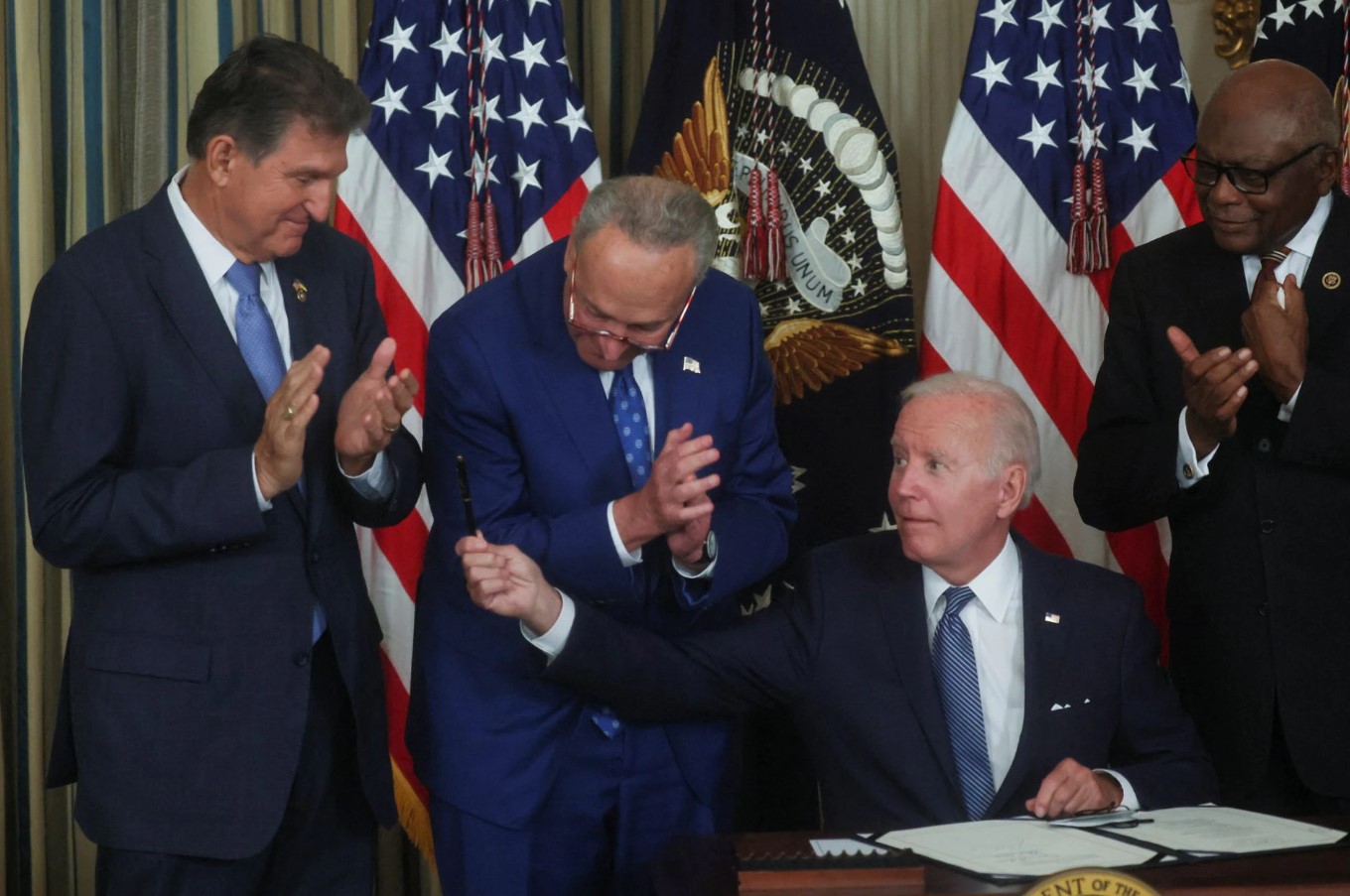 President Joe Biden holds out his pen to U.S. Sen. Joe Manchin, D-WV, as Senate Majority Leader Chuck Schumer, D-NY, and U.S. House Majority Whip James Clyburn, D-SC, look on after Biden signed "The Inflation Reduction Act of 2022" into law during a ceremony in the State Dining Room of the White House in Washington, D.C. Aug. 16, 2022.