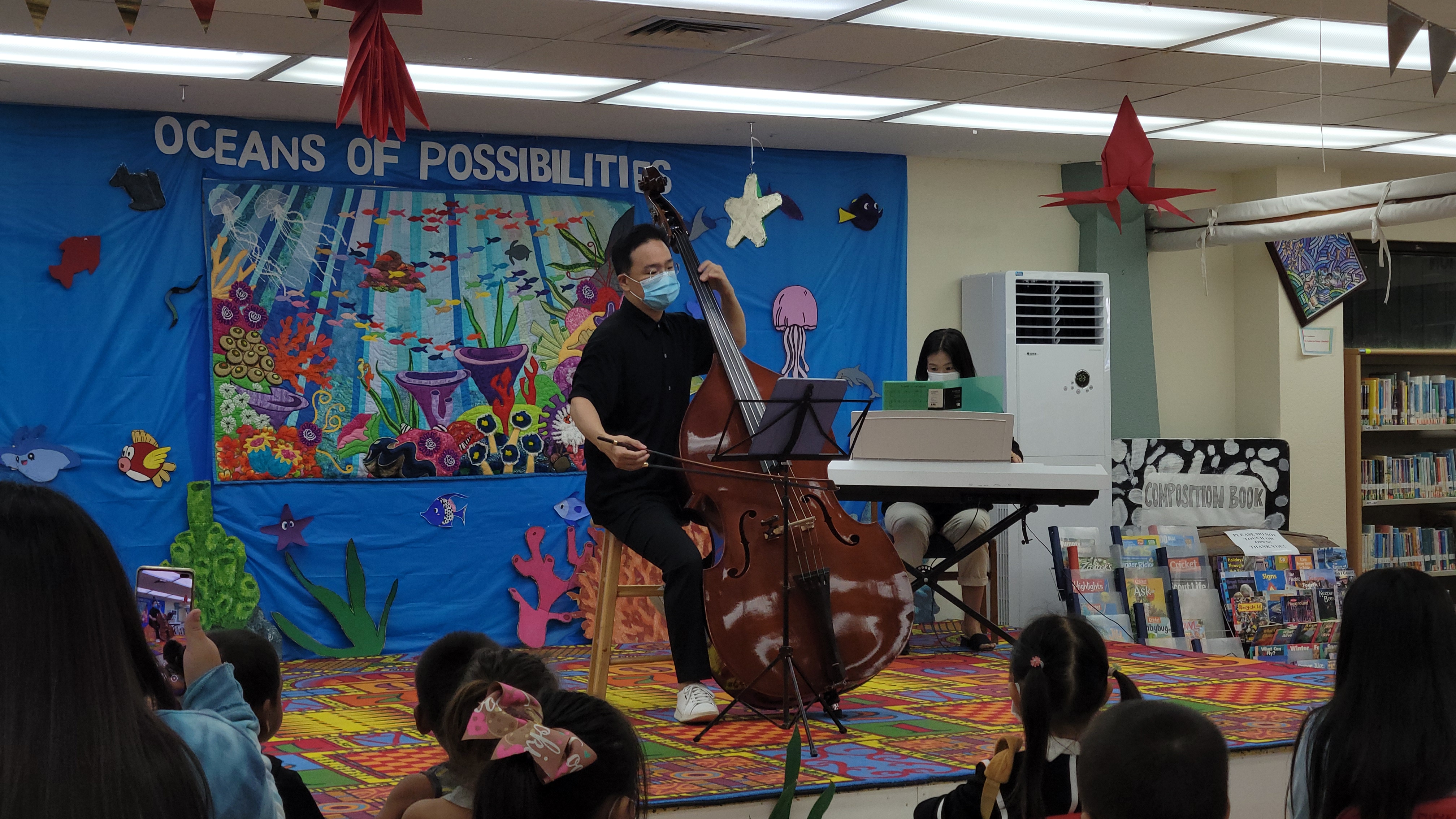 Accompanied by his sister Eunsil Son on the piano, double bassist Changwoo Sohn performs at the Joeten-Kiyu Public Library on Saturday.