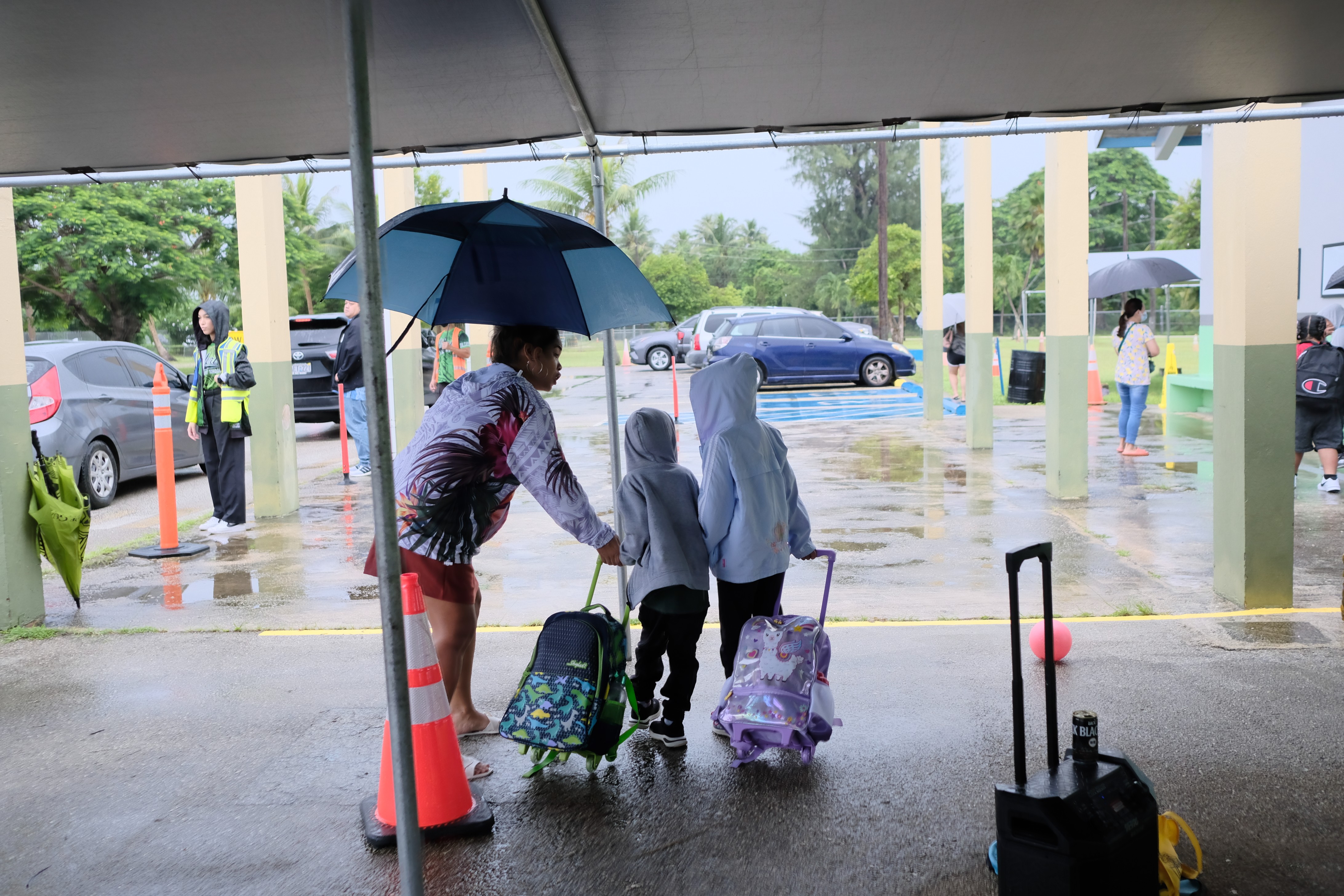 Oleai Elementary School Vice Principal Alyssa Pangelinan assists students on a rainy first day of the new school year.