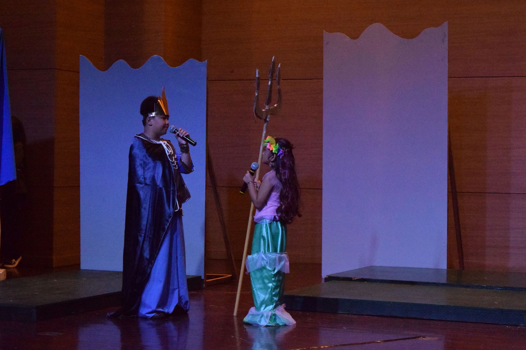 Ariel holds King Triton's trident as he talks to her.