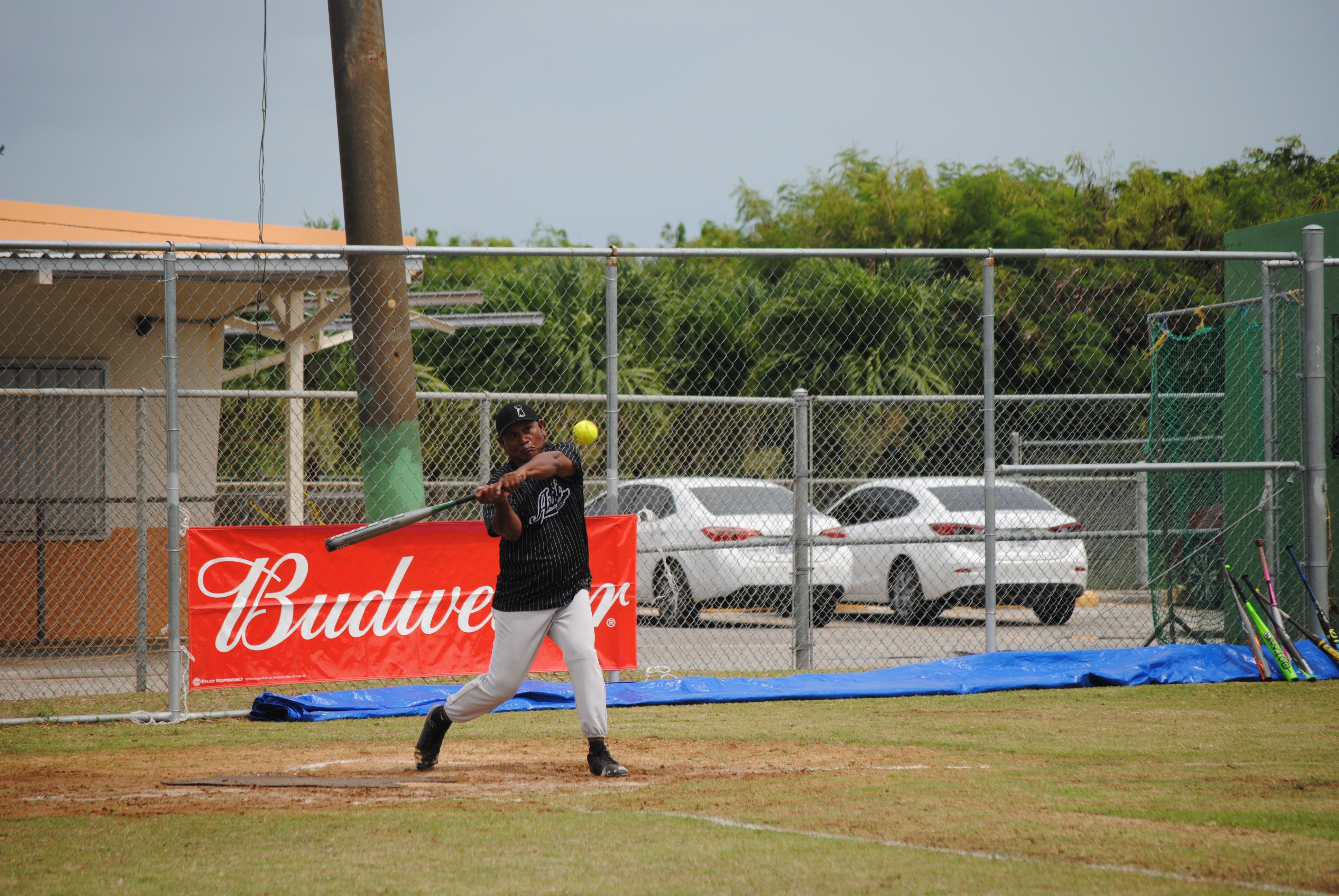 Asahi's Darwin Masaharu connects a hit during a 2022 Budweiser Belau Amateur Softball League game at Dandan baseball field.