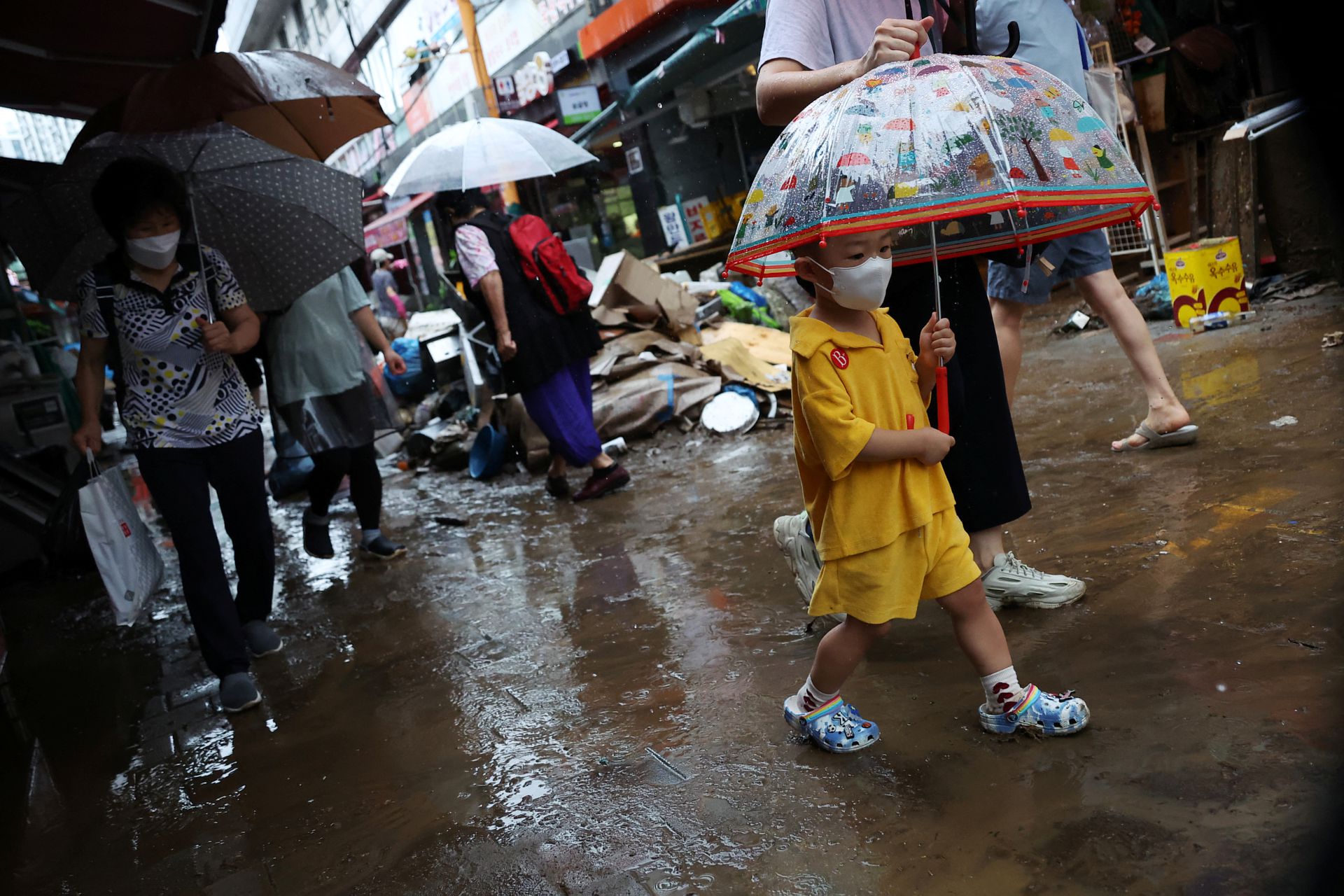A boy using an umbrella makes his way through a road that was flooded after torrential rain at a traditional market in Seoul, South Korea, Aug. 9, 2022.