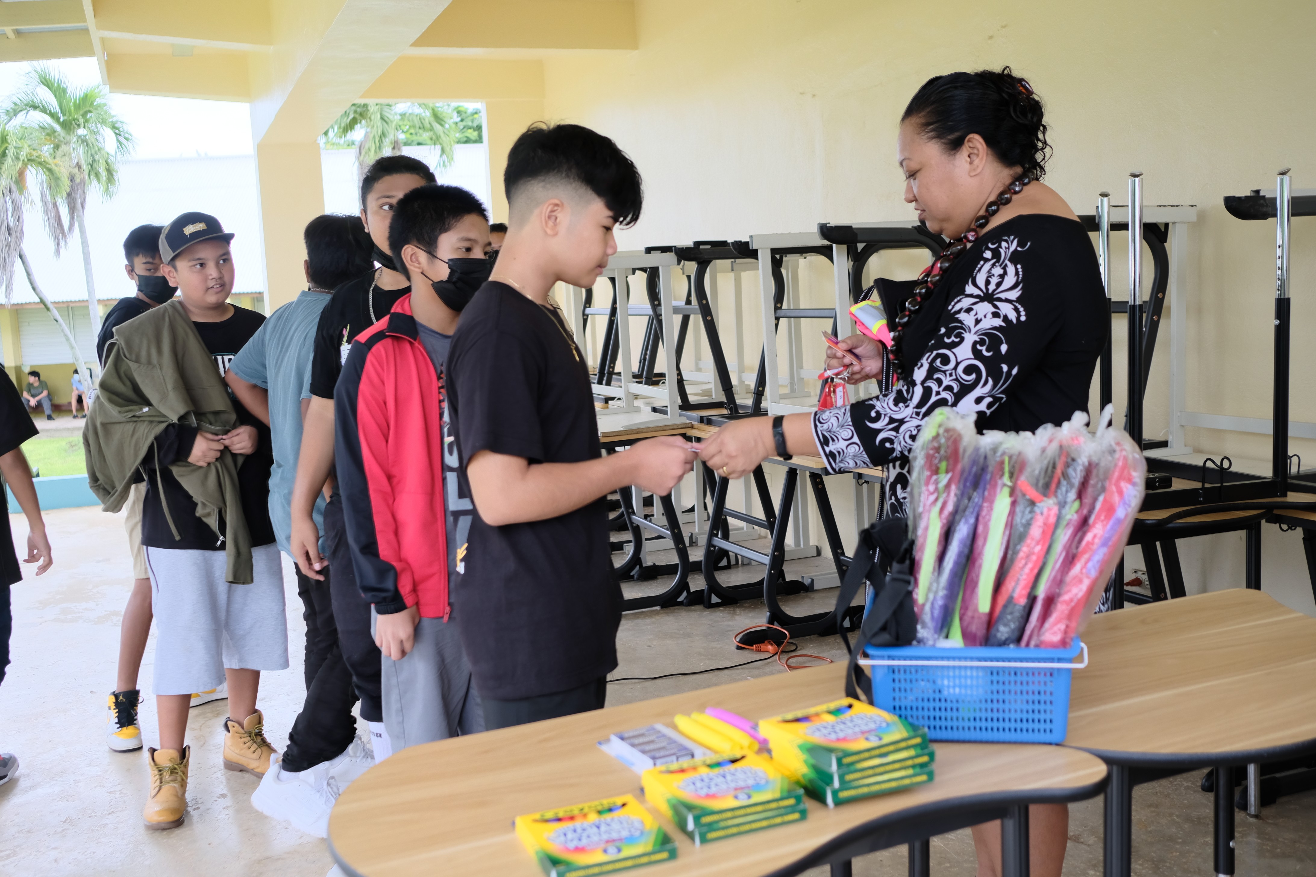 Francisco M. Sablan Middle School Principal Cherlyn C. Osung hands out free school supplies to students.