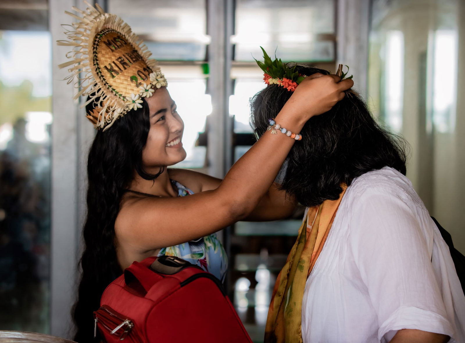 Miss Kiribati Paepae Kilei garlands a newly arrived traveler.