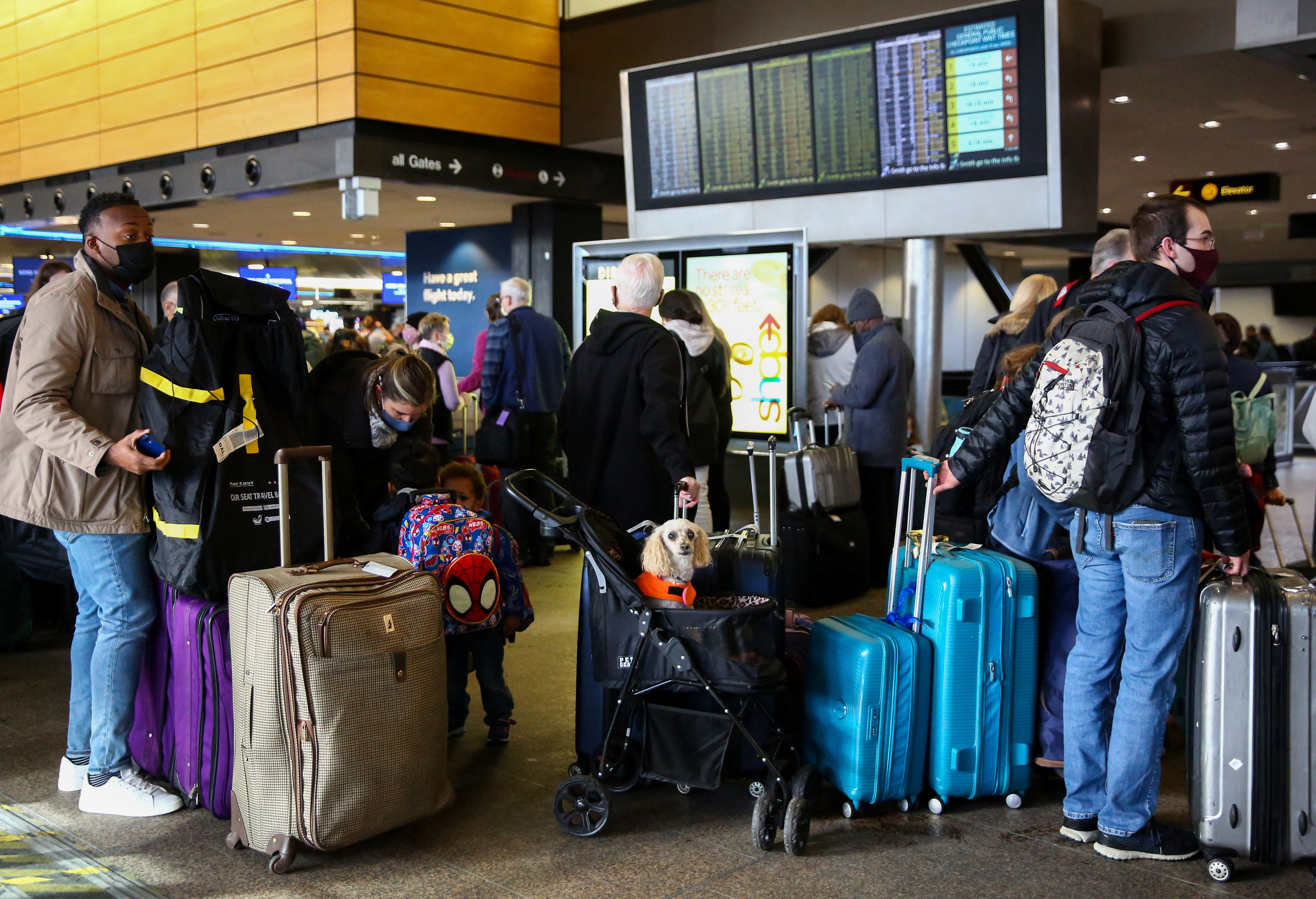 People wait in long check-in lines after dozens of flights were listed as cancelled or delayed at Seattle-Tacoma International Airport in Seattle, Washington, Dec. 27, 2021.