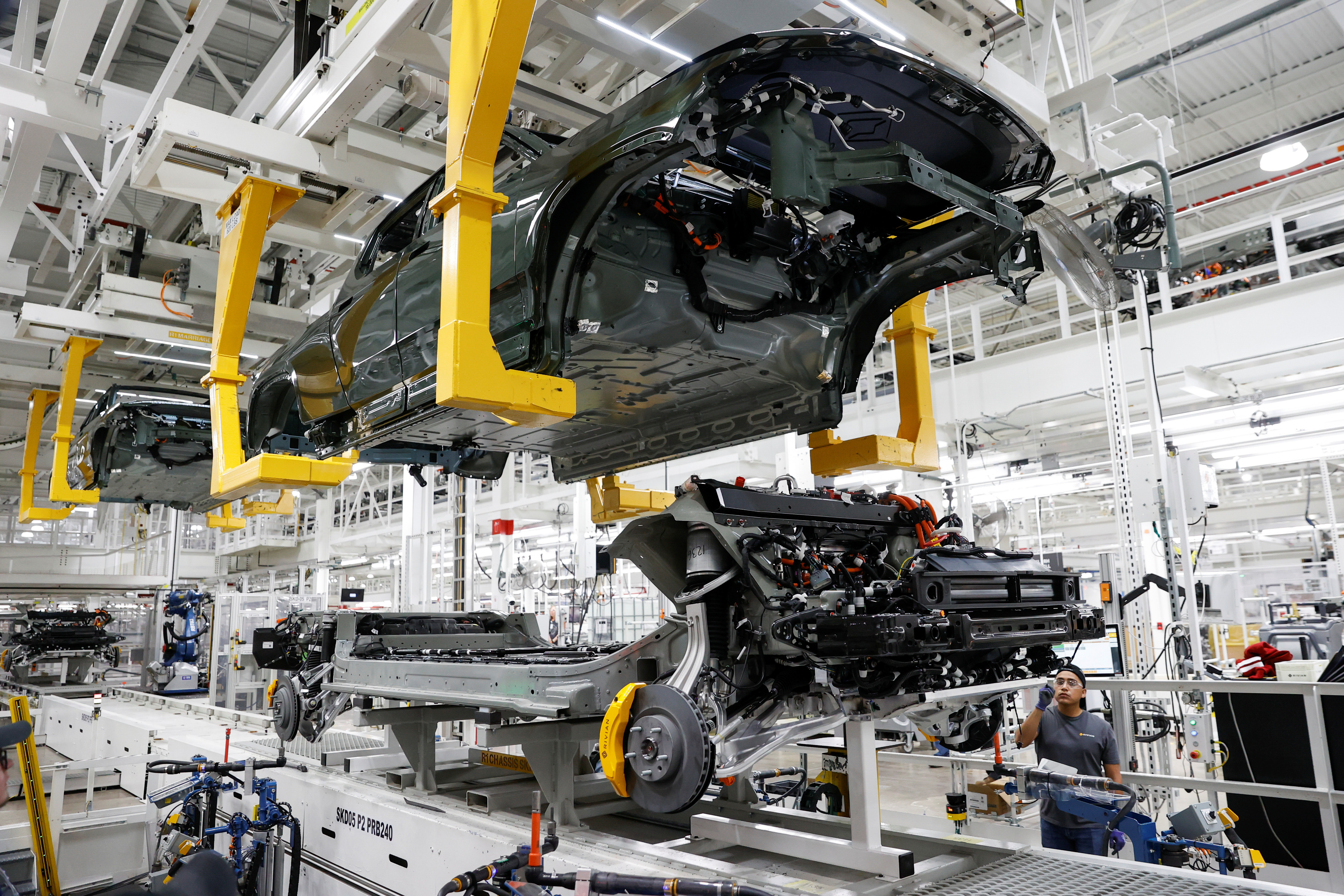 An employee works on an assembly line at startup Rivian Automotive's electric vehicle factory in Normal, Illinois,  April 11, 2022.  