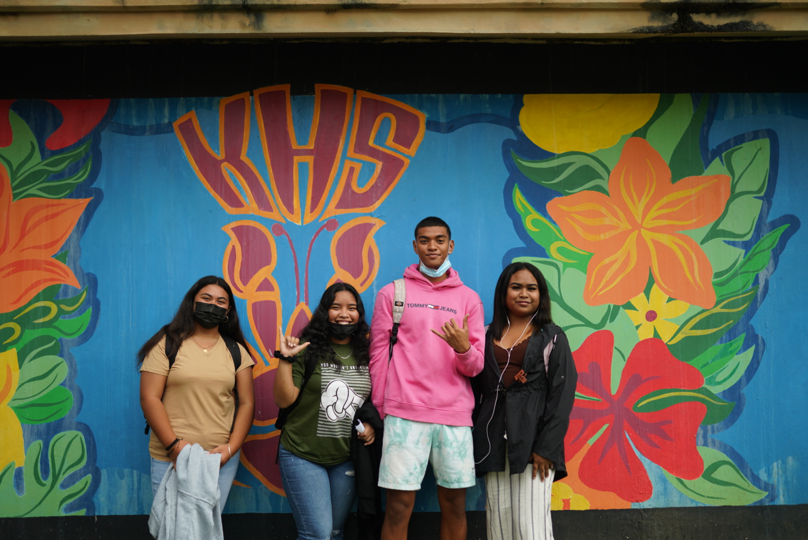 Kagman High School students pose for photo with their school’s colorful mural in the background.