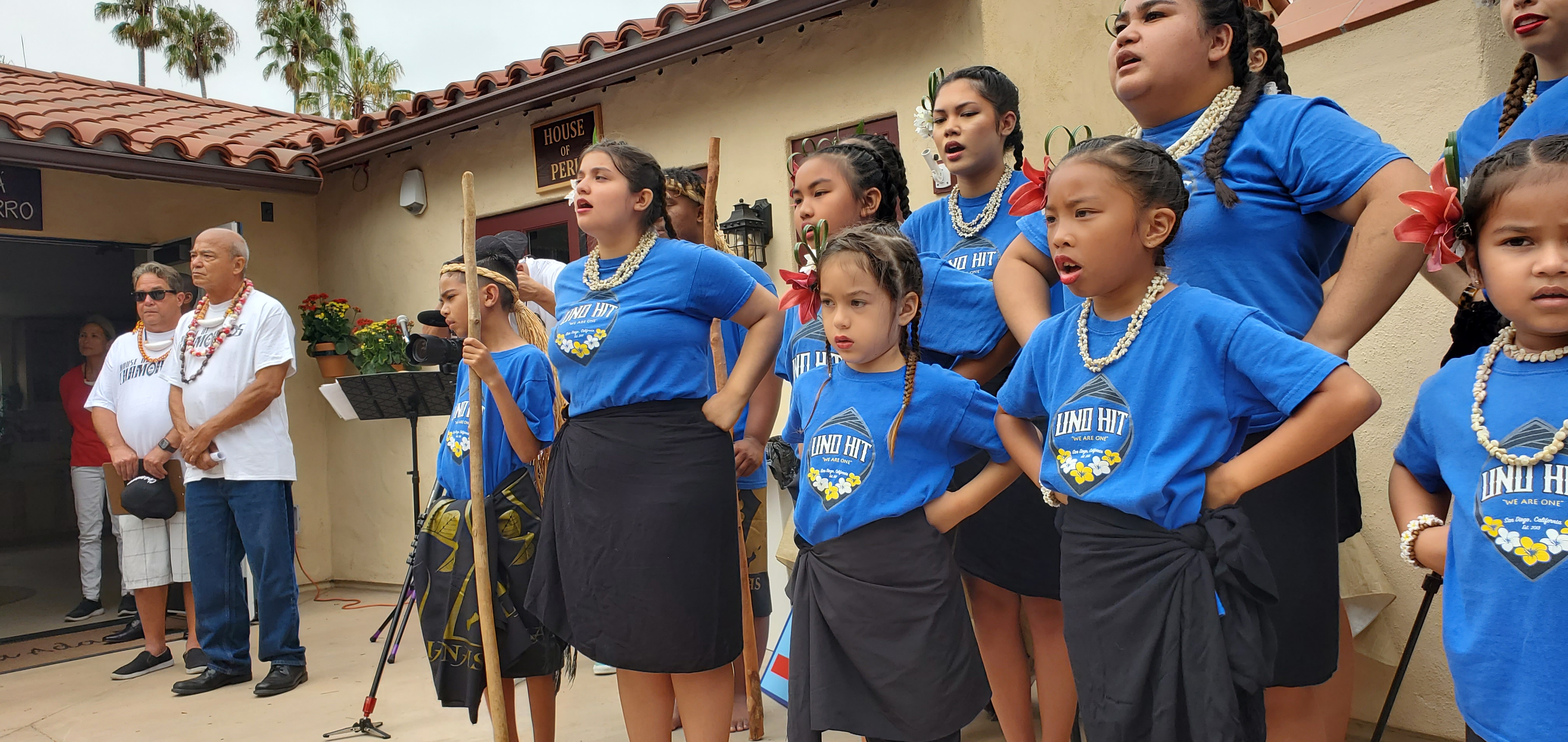 San Diego based dancers from Uno Hit perform a chant during the grand opening ceremonies of the House of Chamorros while House of Chamorros President Jeff Macaraeg looks on.