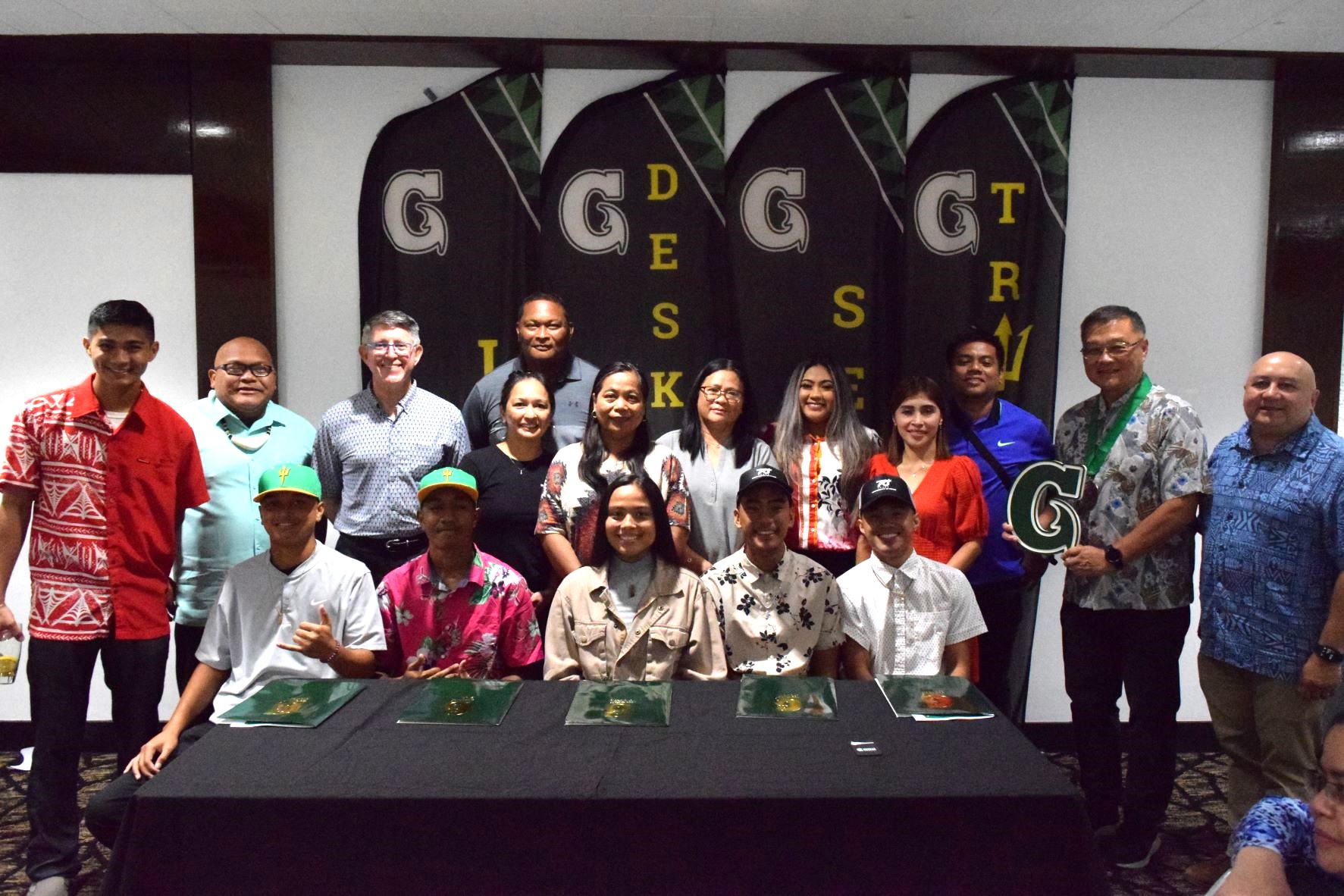 The five CNMI student athletes, seated, and their parents, pose for a photo with University of Guam President Dr. Thomas Krise, third left back row, UOG Enrollment Management & Student Success Dean Lawrence Camacho, right, Northern Marianas Sports Association President Jerry Tan, second right, and other UOG officials.