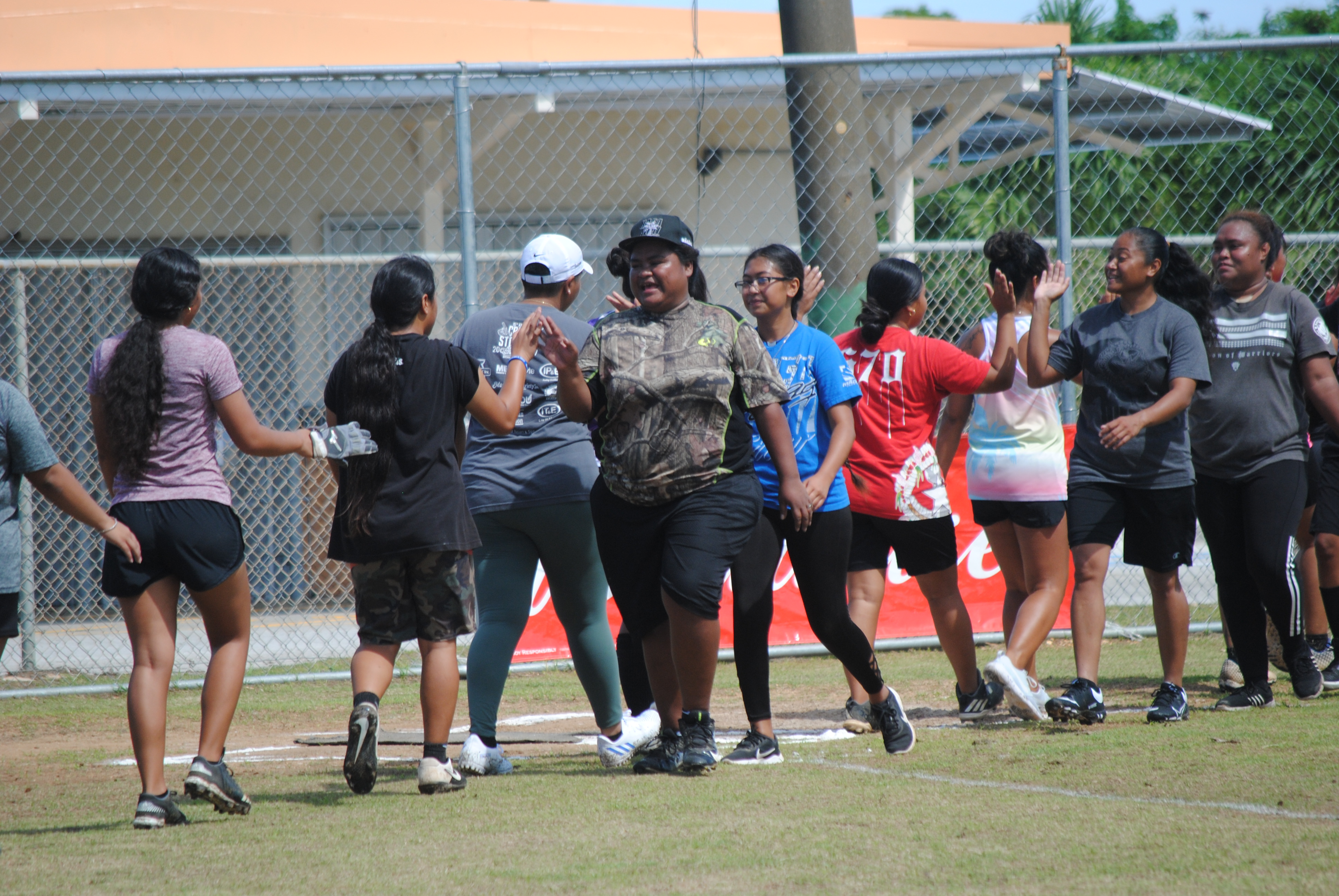 The Queens of Diamonds and the Hotshots exchange high-fives  after their 2022 Budweiser Belau Amateur Softball League game at the Dandan baseball field.