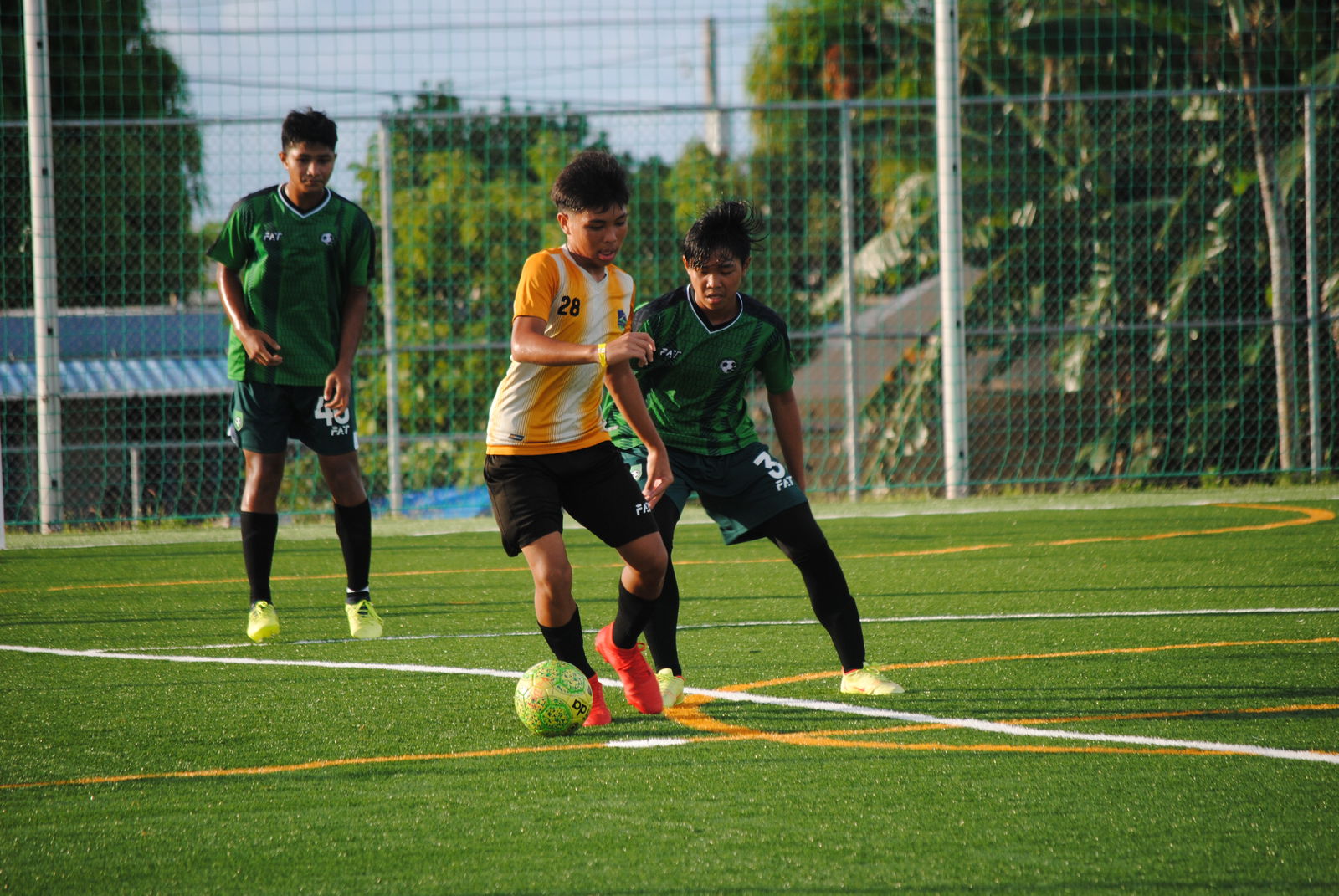 Kanoa 2’s Paul Lizama protects the ball as a Tan Holdings defender closes in during the U16 Boys Division championship game of the 2022 Youth Summer Cup on Saturday at the NMI Soccer Training Center in Koblerville.