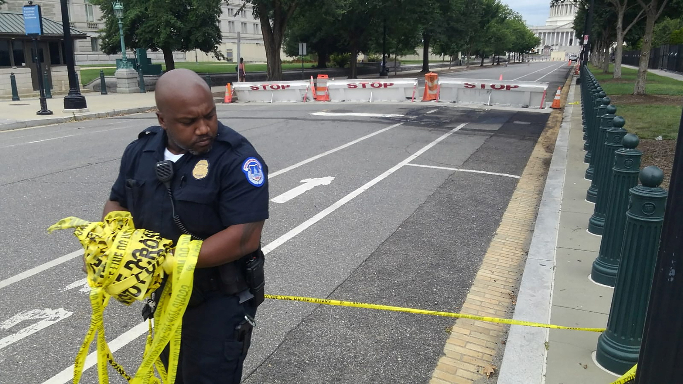 A U.S. Capitol Police officer removes security tape from an area where a man crashed his car into a barricade near the U.S. Capitol and fired shots into the air before killing himself, in Washington, D.C. Aug. 14, 2022.