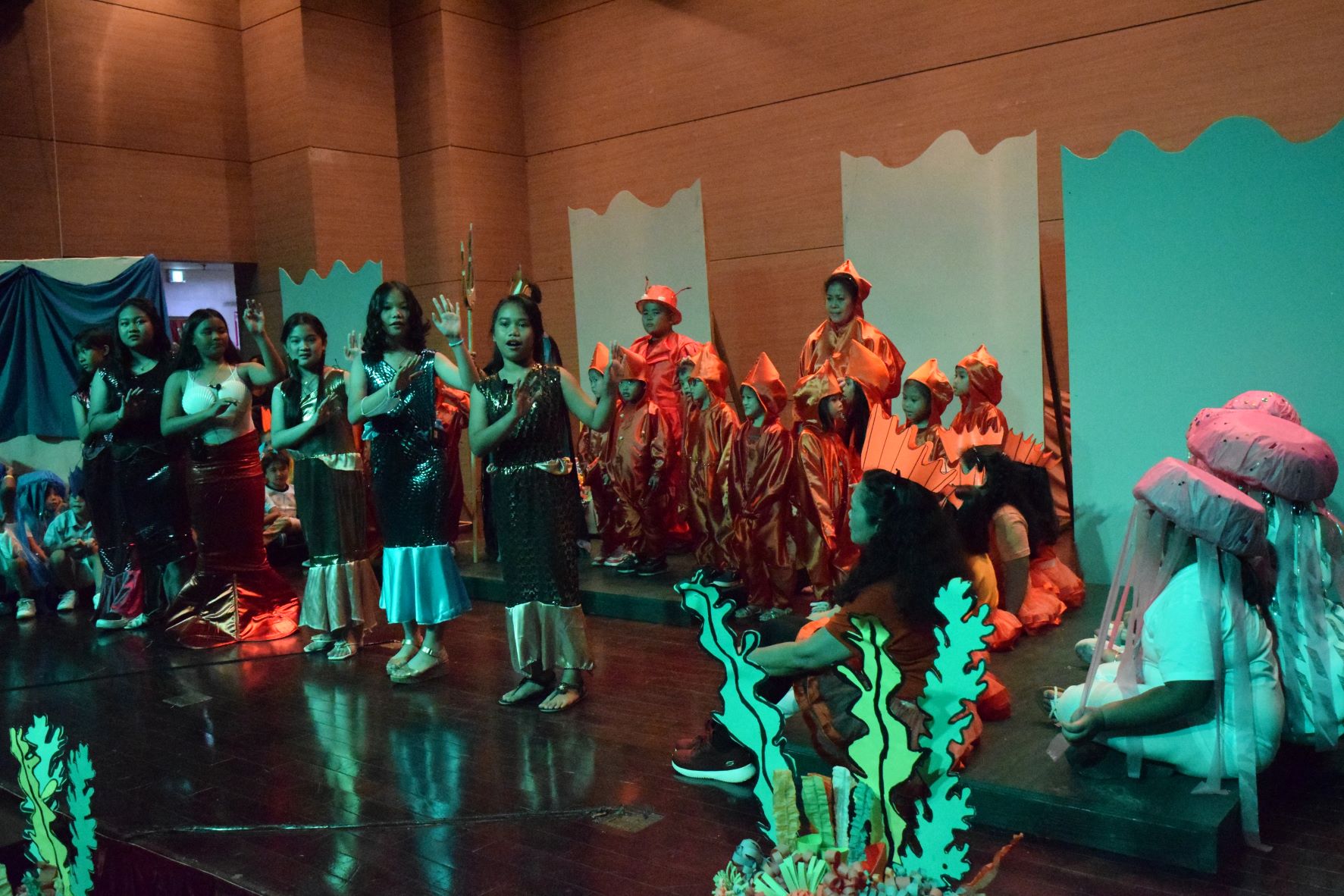 Ariel's sisters are portrayed by, from center to left, fifth grader Aira, Jewel, fourth grader Mary Joy, fifth graders Annabella, Jamie and Sarang. In the back are Sebastian played by Leyland Duenas, and Kinder 5 students as the squids with teachers Maricel Javier and Aida Marcelo.