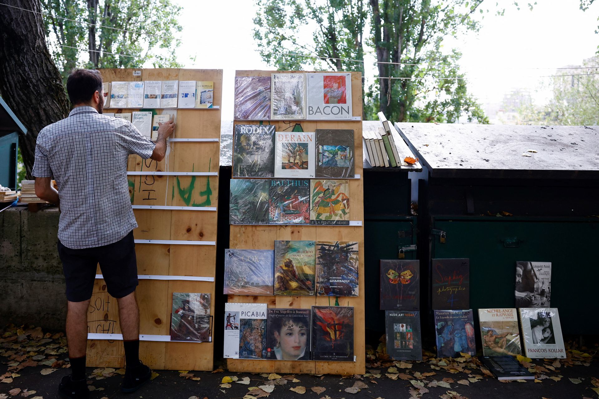Traditional street bookseller Rachid Bouanou places books on shelves along the banks of the River Seine in Paris, France, Aug. 18, 2022.