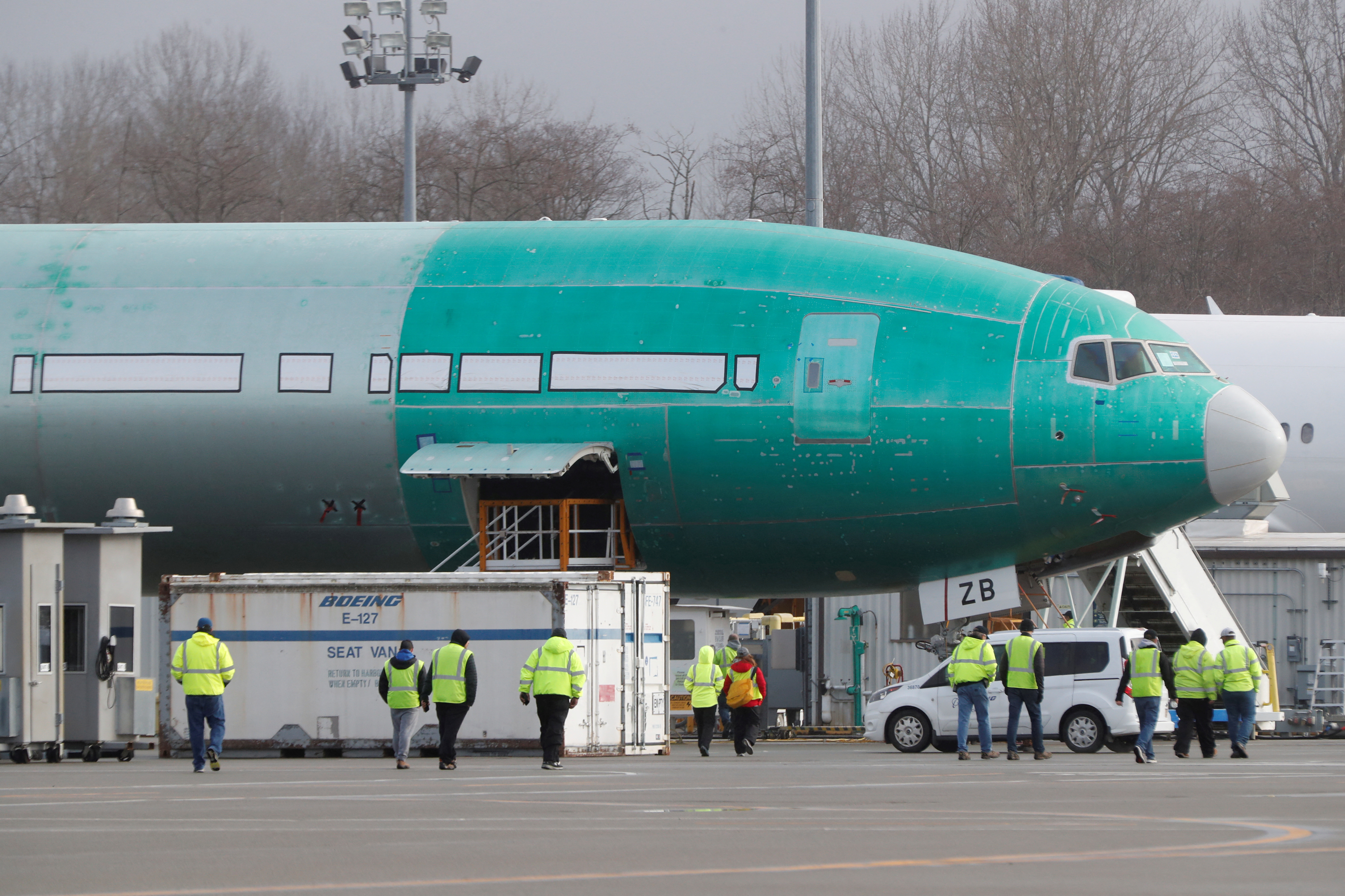 Boeing employees walk near a partially finished Boeing 777X airplane at the company's plant in Everett, Washington, Jan. 25, 2020.
