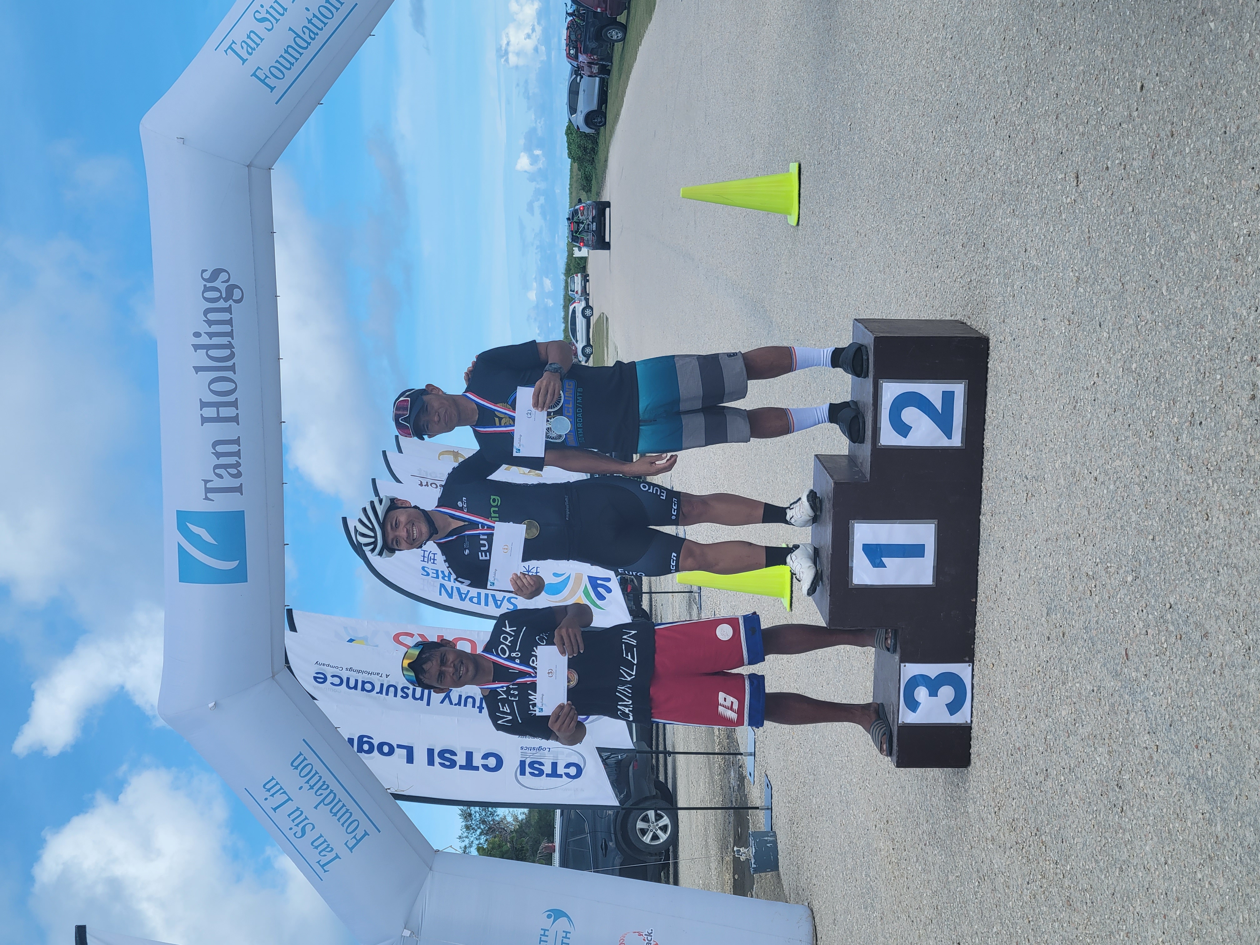 First placer Jonathan Martin, center, with second placer Joel Buco, right, and third placer Fred Remillosa pose on the  podium at the conclusion of the 50th Tan Holdings Anniversary 50KM Bike Race on Saturday in Marpi.