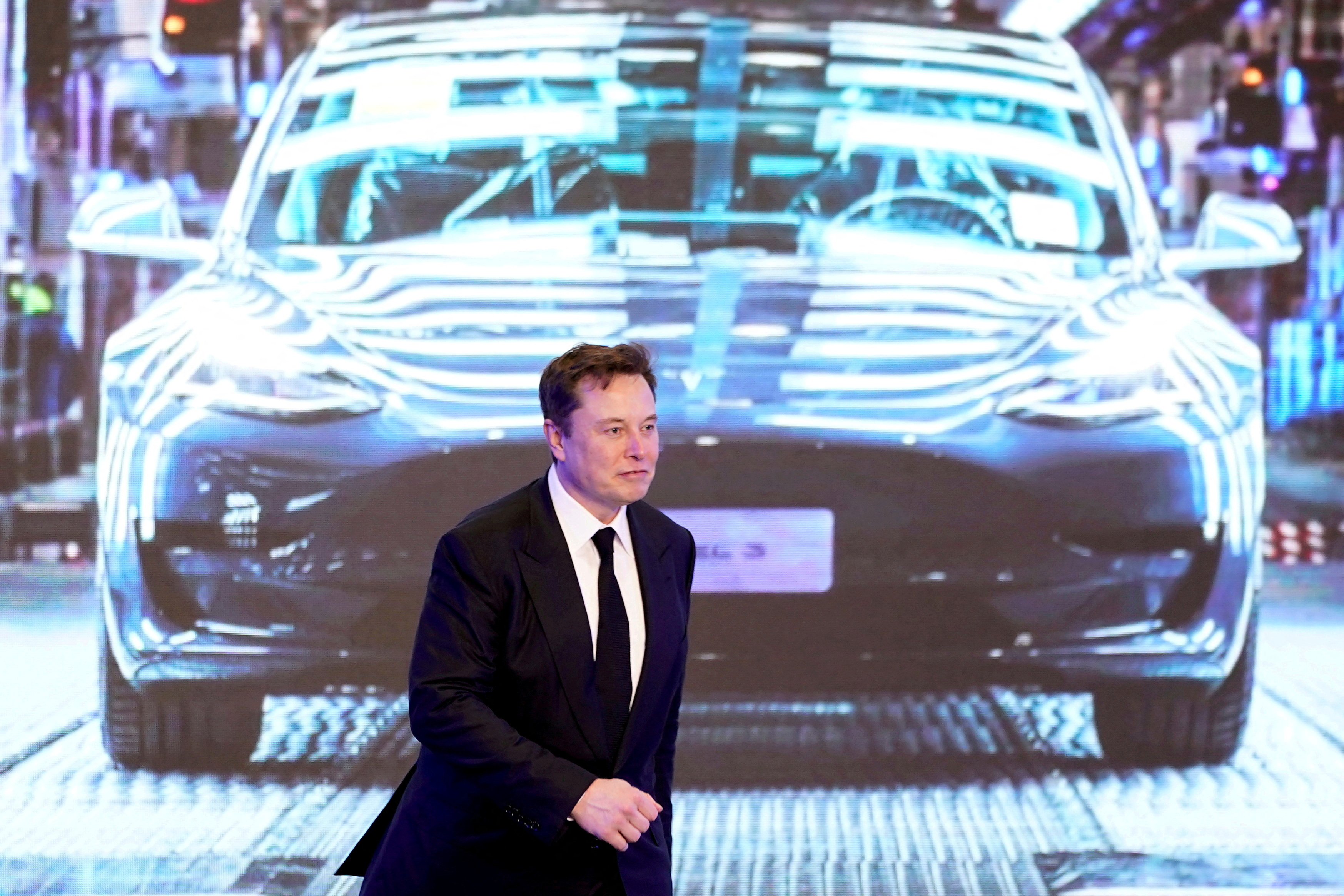 Tesla Inc CEO Elon Musk walks next to a screen showing an image of Tesla Model 3 car during an opening ceremony for Tesla China-made Model Y program in Shanghai, China, Jan. 7, 2020.