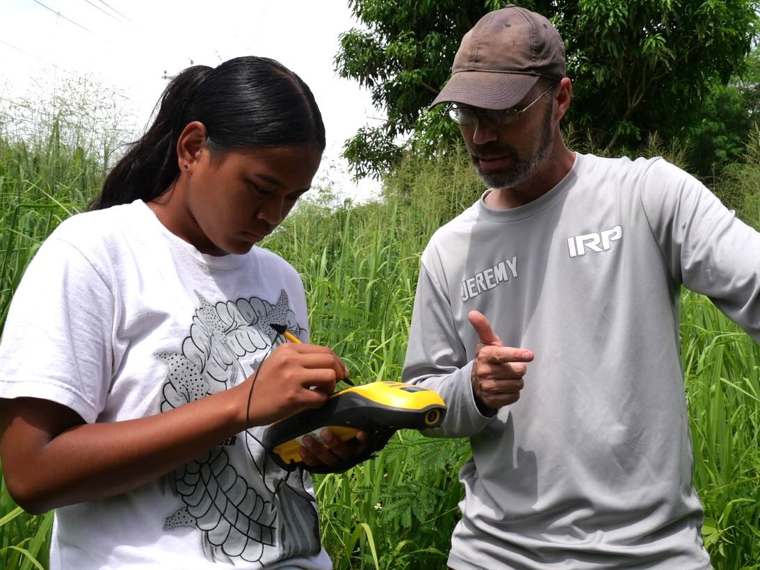 IRP Lead Archaeologist Jeremy Freeman instructs Youth Affairs Intern Heather Moses on how to use Trimble to perform surveys.