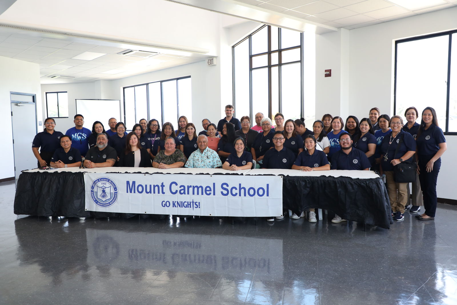 Mount Carmel School’s faculty, staff, and members of the board of directors gather for a group photo after announcing Frances Taimanao as the school’s new president.