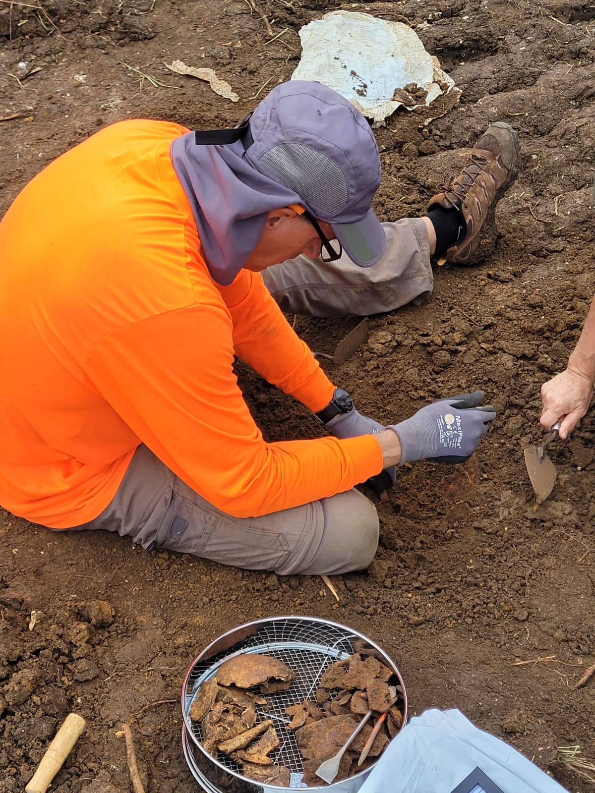 A field researcher extracts human remains from the soil at the site of the Banzai attack in Tanapag during the Battle of Saipan. At the bottom of the picture are fragments of human bones and a helmet.