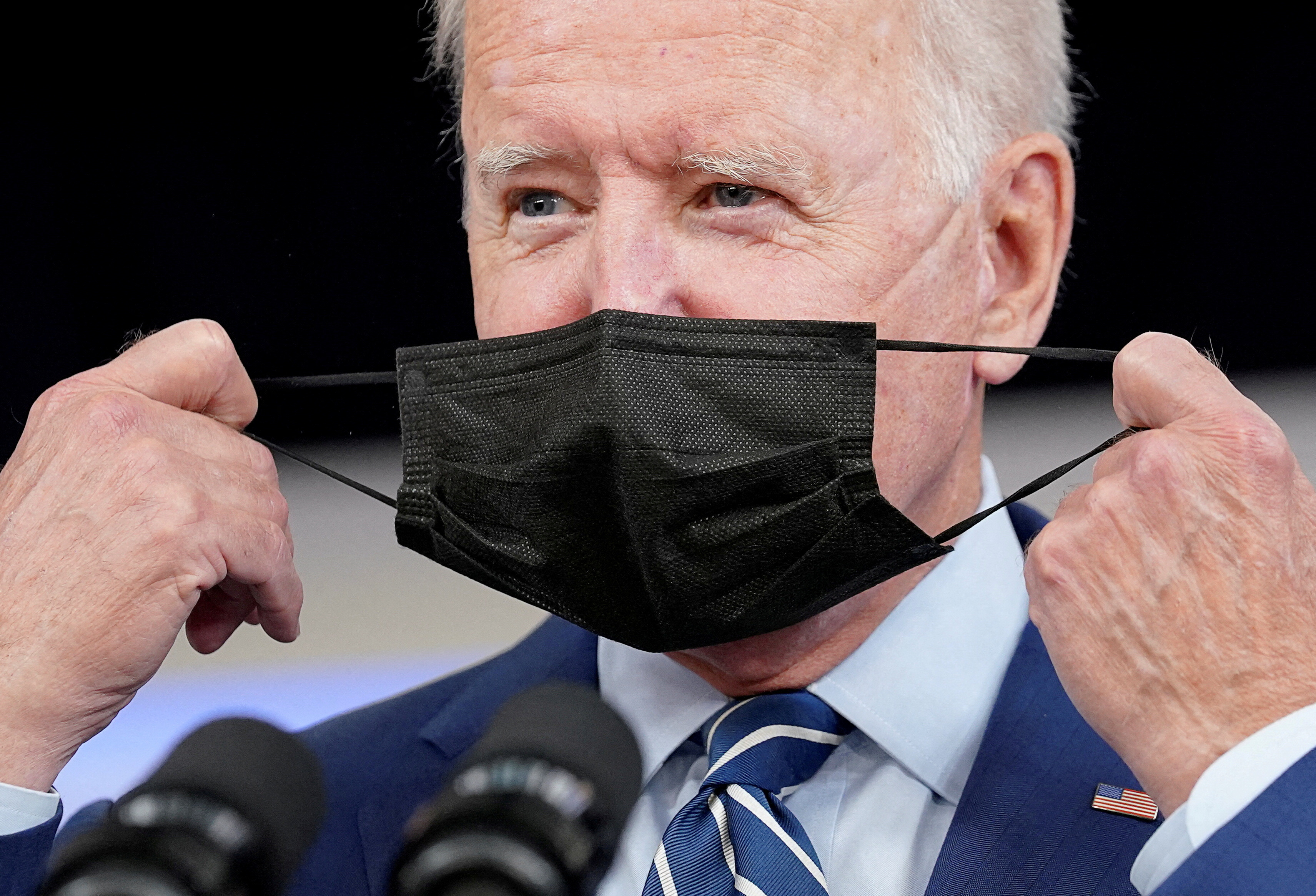 President Joe Biden removes his face mask prior to receiving his coronavirus disease booster vaccination in the Eisenhower Executive Office Building's South Court Auditorium at the White House in Washington, D.C., Sept. 27, 2021.