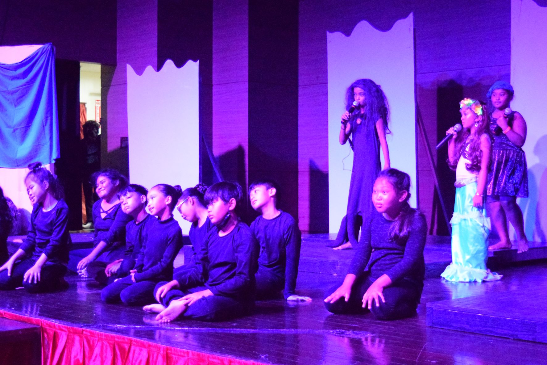 Ursula portrayed by Lara Yzabelle Zapanta and Ariel confront each other. Also in photo are Ursula's tentacles, fourth graders Angelee Agdoro, Christiana Ngiramos, Geri Liam Espiritu, Giselle Hernandez, Rayne Roquelara, Carmelo Salamat, Jarl Mabaquiao and Johana Sarabia. Behind Ariel is eel Flatson, played by Rihanna Sansi.