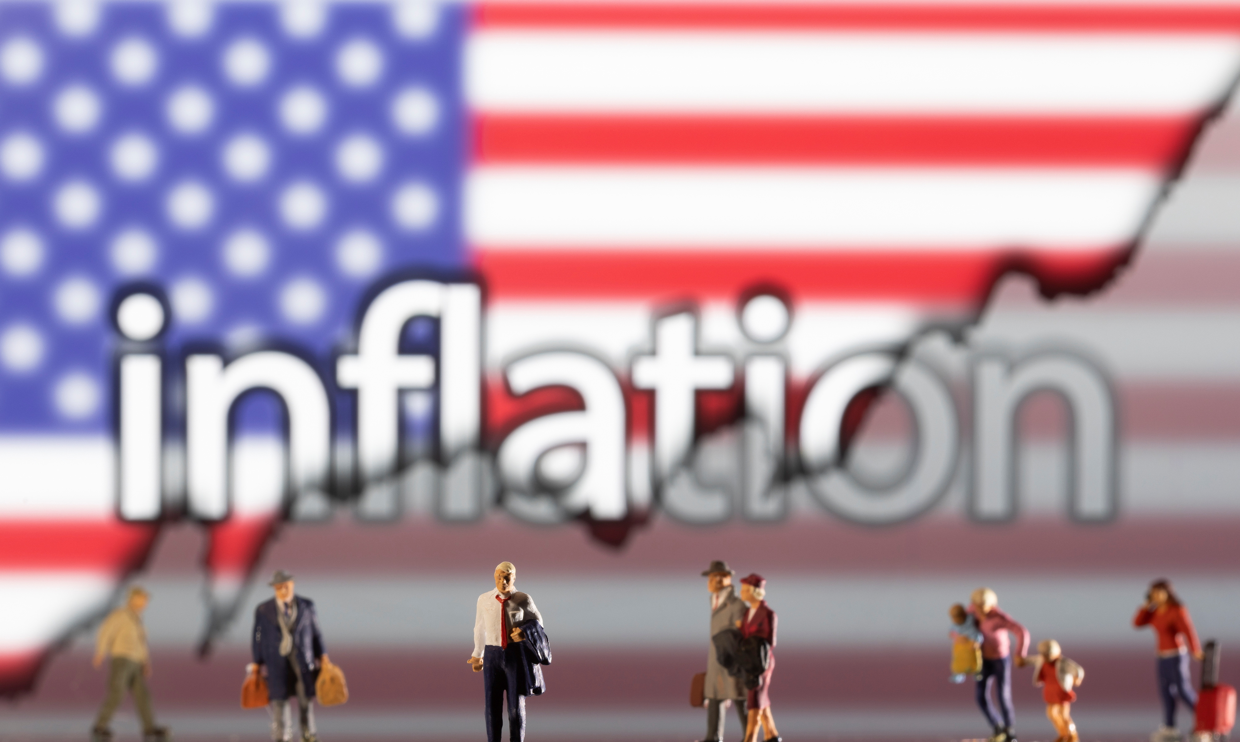 Small figurines are seen in front of displayed word "Inflation," U.S. flag and rising stock graph in this illustration taken Feb. 11, 2022.
