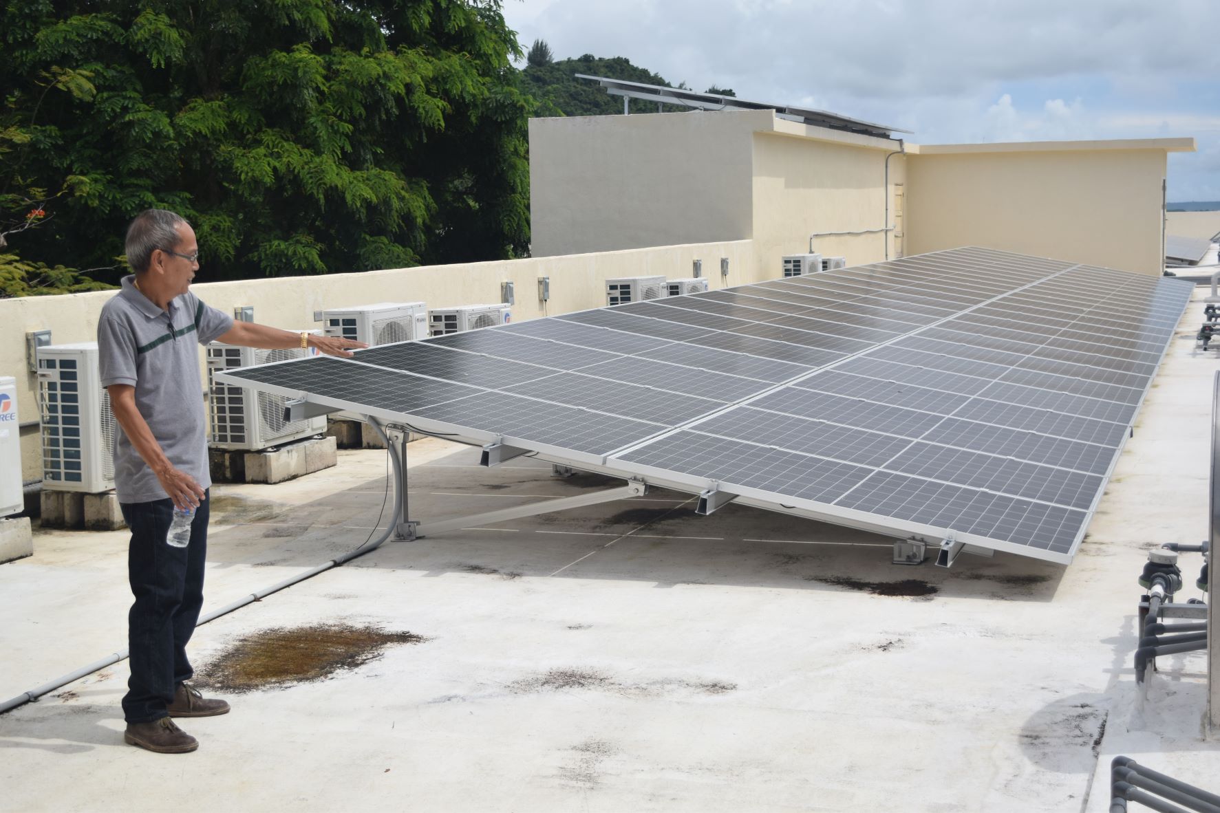 Zen Homes Apartment mechanical and electrical engineer Renato Abarquez stands next to the photovoltaic panels on the roof of the four-story apartment in Gualo Rai on Friday.