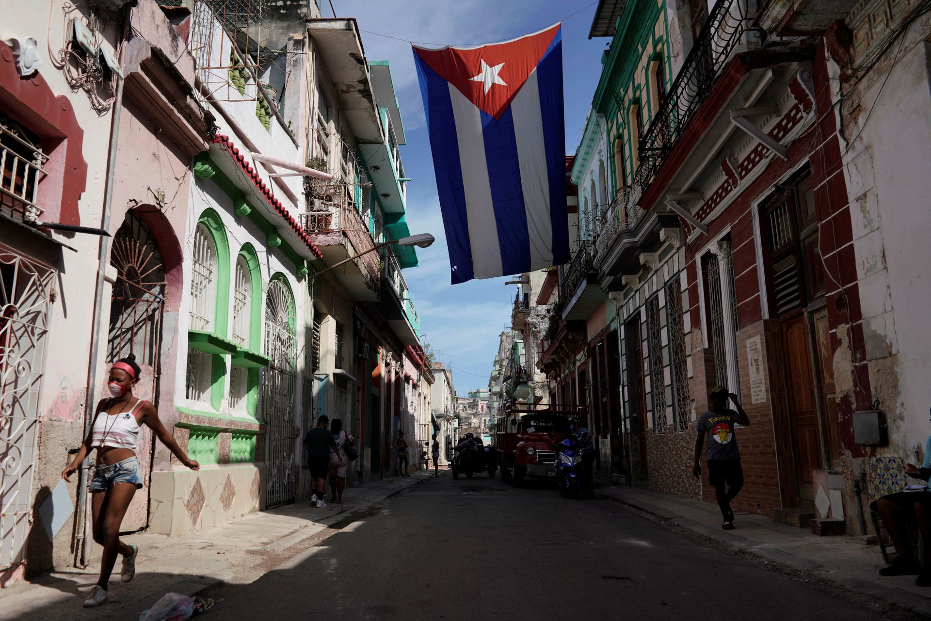 People walk under a Cuban flag hanging in downtown Havana, Cuba, Oct. 8, 2021.