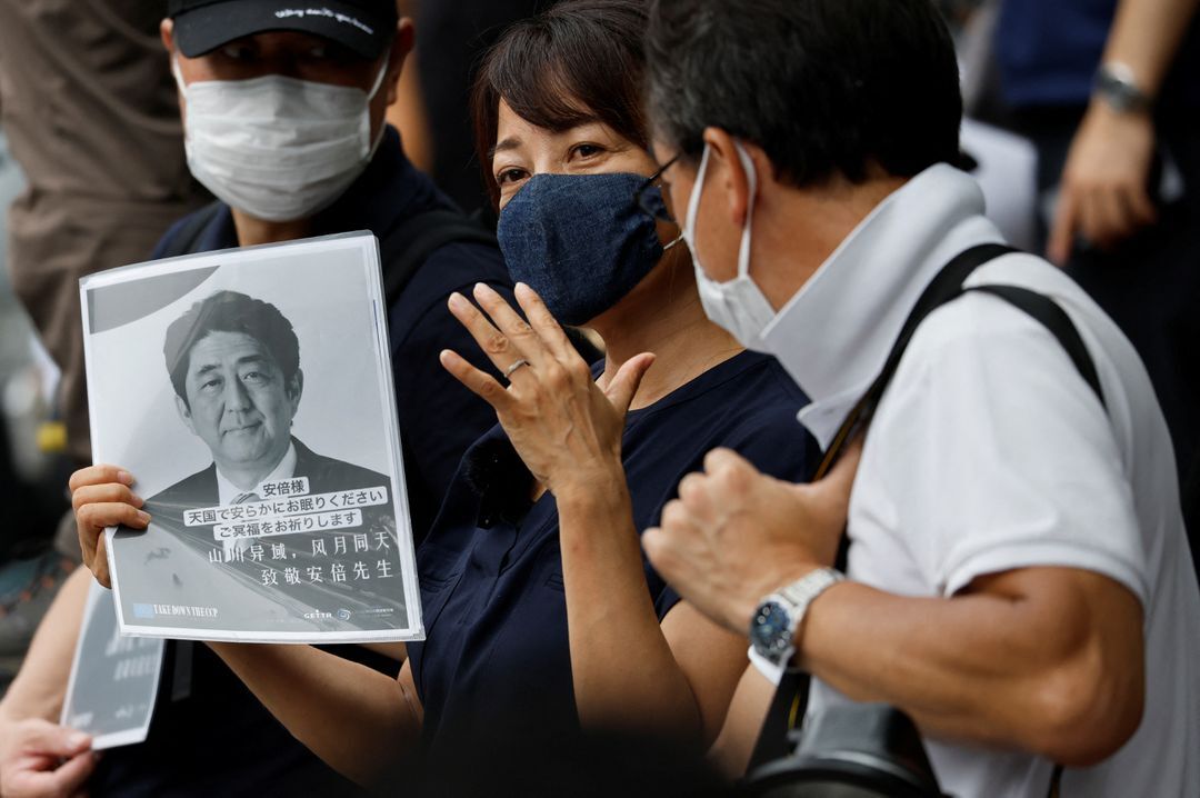 A woman holds a farewell message for late former Japanese Prime Minister Shinzo Abe outside the Zojoji temple where the funeral of Abe, will be held in Tokyo, Japan. 