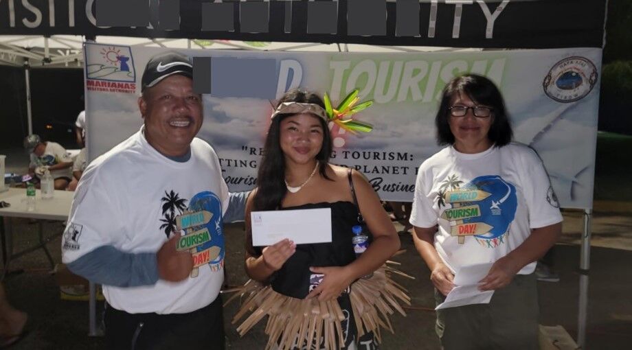 Tinian Mayor Edwin Aldan,  left,  awards Sienna Lazaro a prize for her cultural attire during the World Tourism Day Sunset Walkathon  on Sept. 27,  2022,  in  Tinian.  Also  pictured  is  Marianas Visitors Authority Tinian Field Supervisor Vida Borja.
