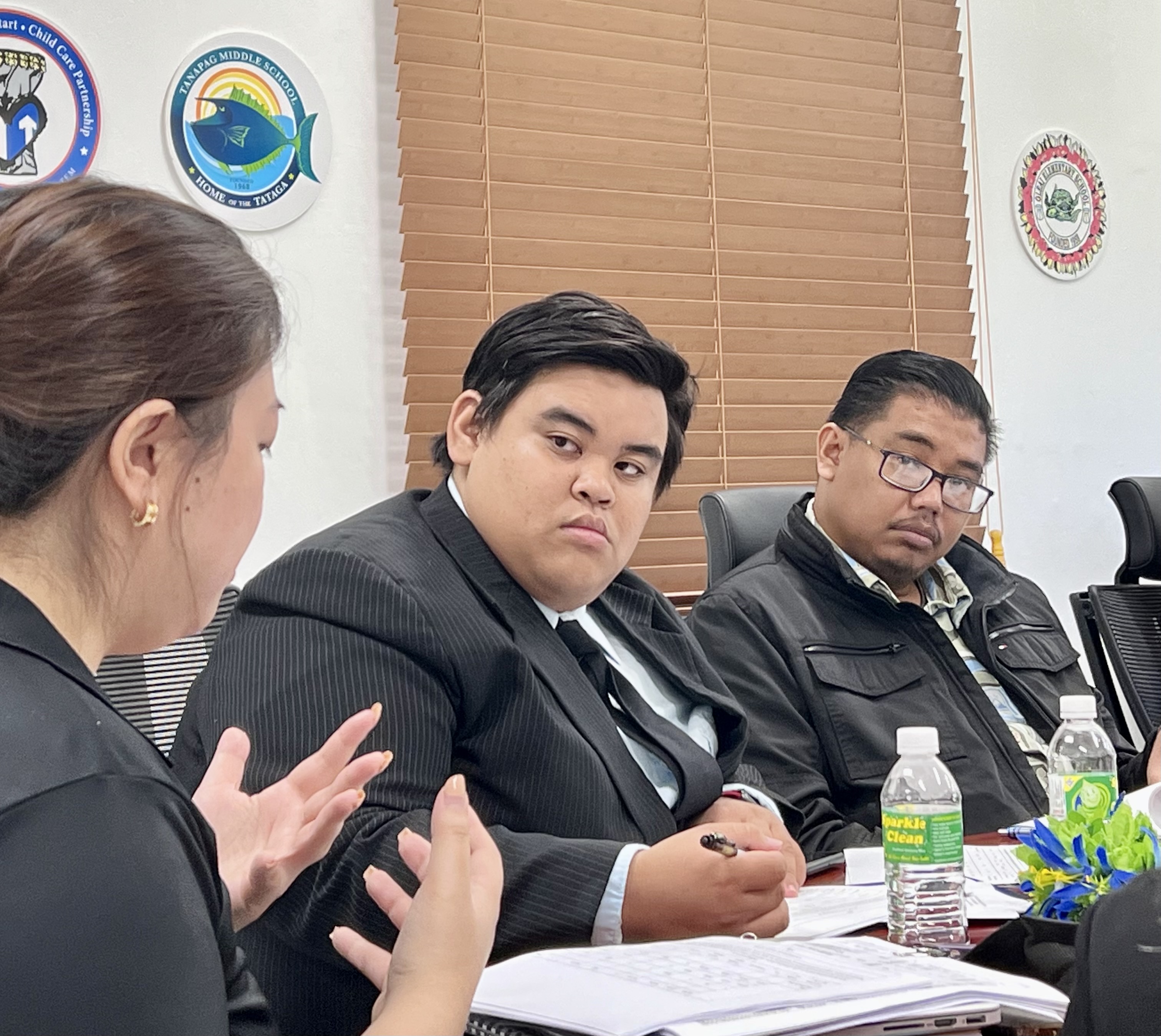 Attending his first Board of Education meeting on Monday, new student representative Ryan Michael Nuera, center,  listens to interim PSS Federal Programs Officer Jacqueline Che, left, back to the camera. Also in photo is BOE Vice Chairman Antonio L. Borja, right.