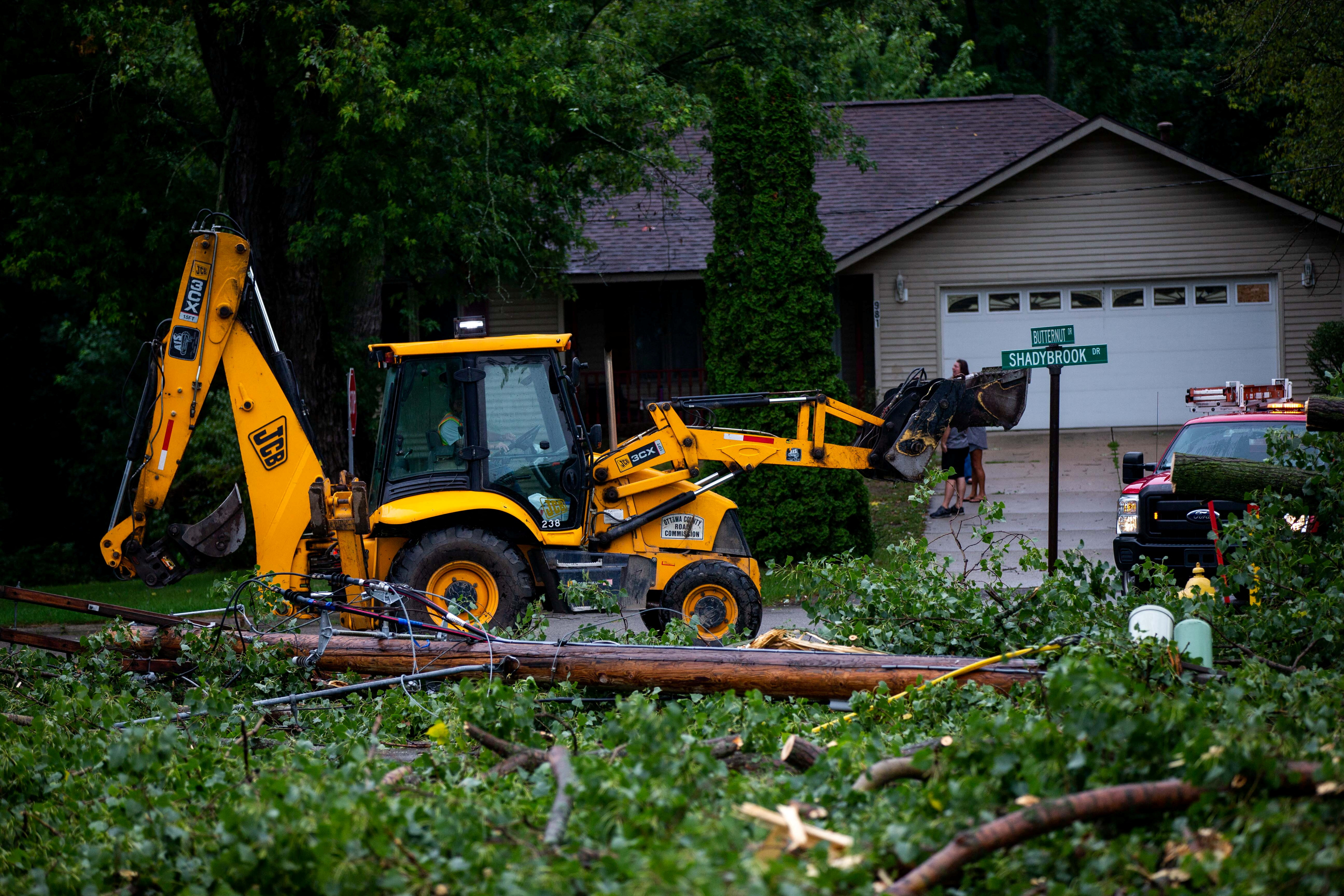 Fallen tree limbs are cleared after thunderstorms and high winds downed power lines and closed roads in Holland, Michigan, Aug. 29, 2022.