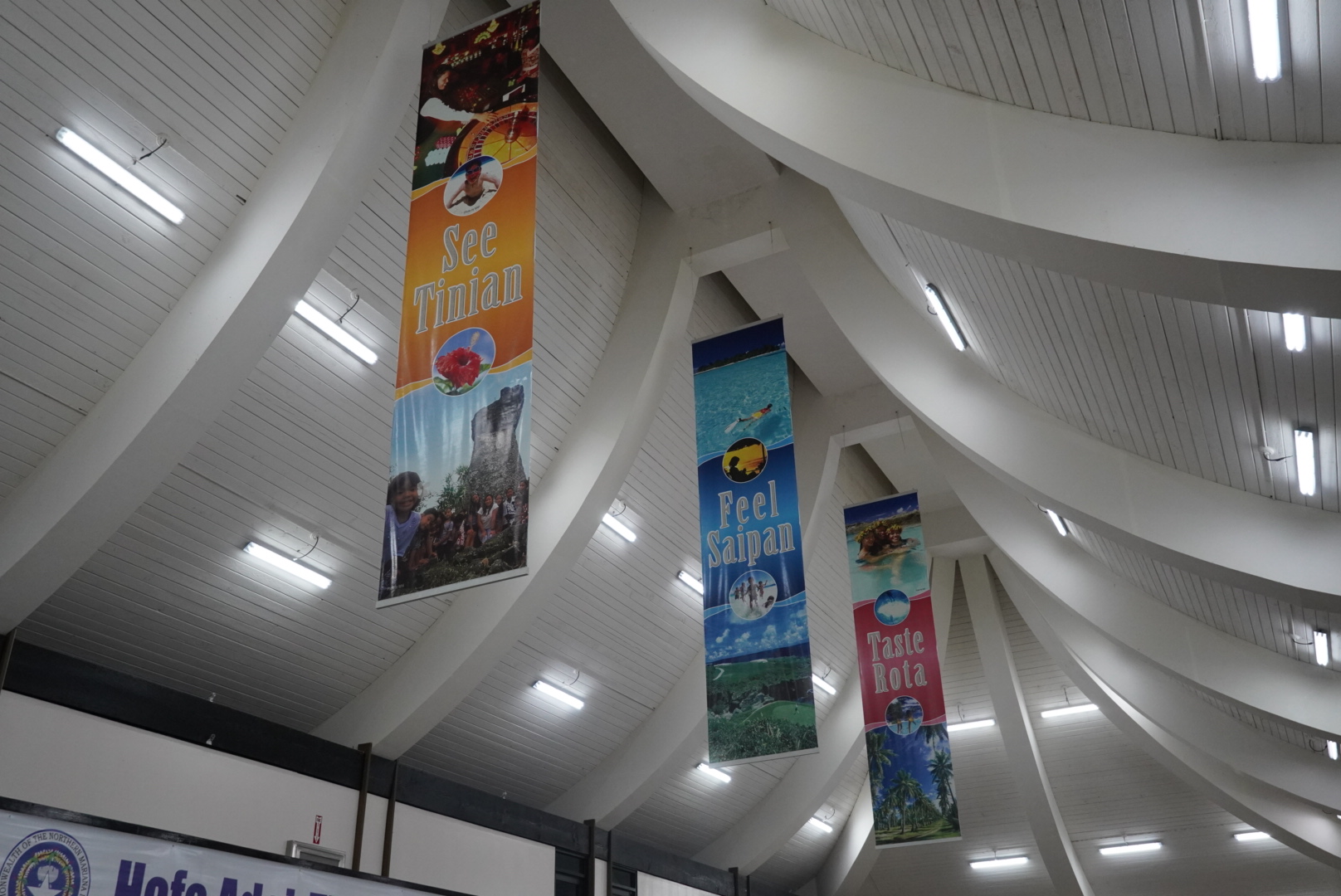 Banners promoting Saipan, Tinian, and Rota are displayed at the Francisco C. Ada/Saipan International Airport arrival terminal.