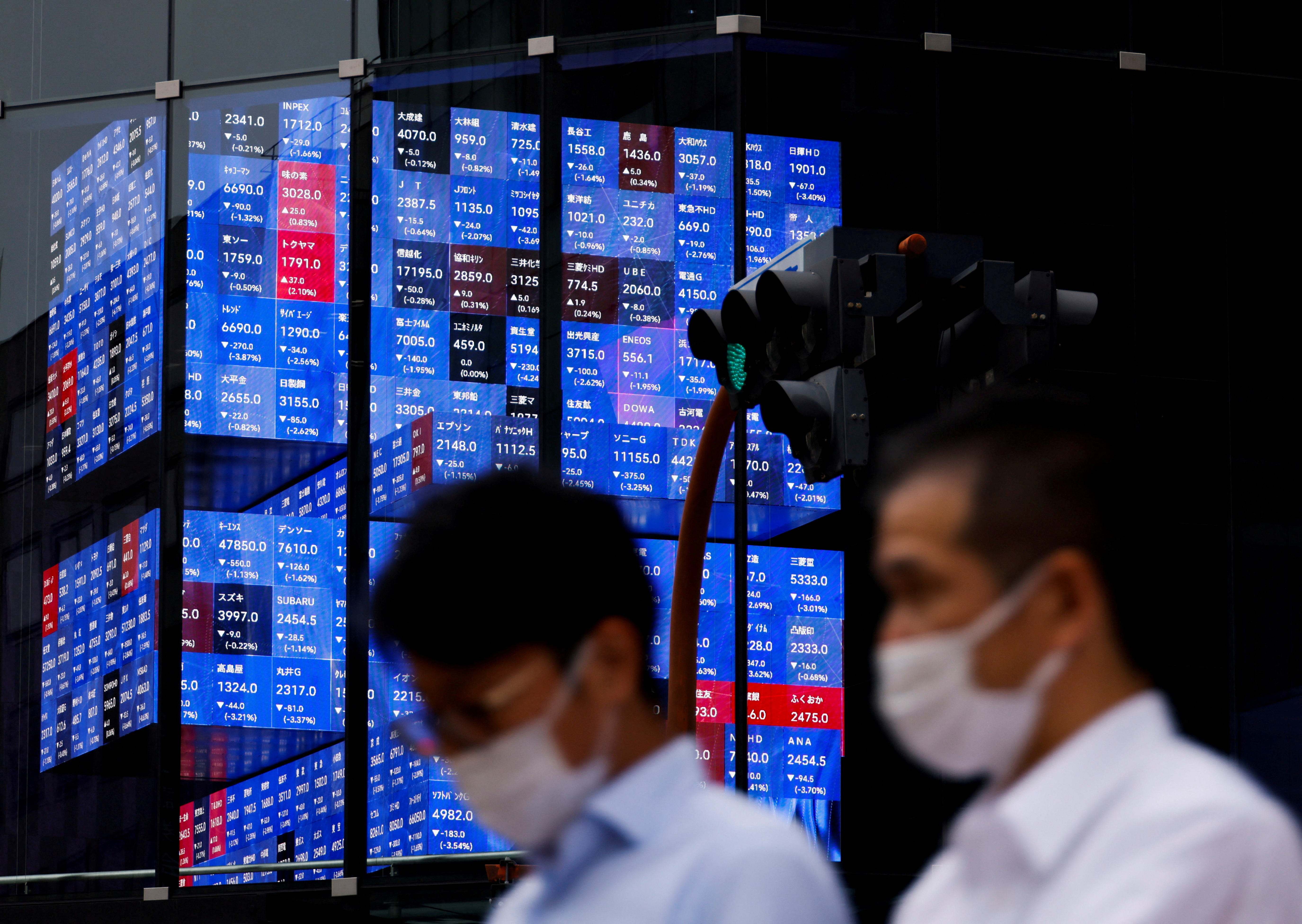People pass by an electronic screen showing Japan's Nikkei share price index inside a conference hall in Tokyo, Japan, June 14, 2022.