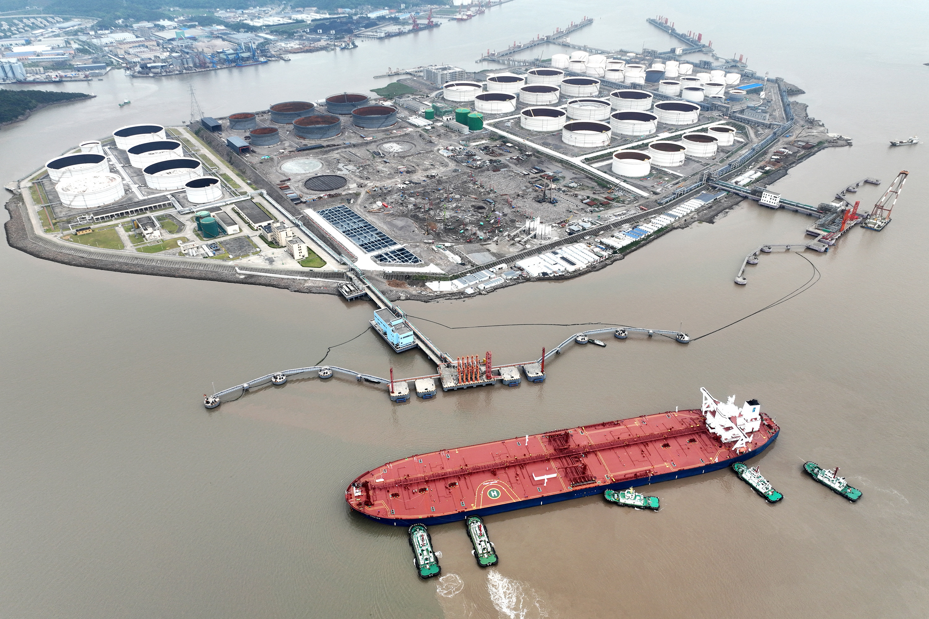 An aerial view shows tugboats helping a crude oil tanker to berth at an oil terminal, off Waidiao Island in Zhoushan, Zhejiang province, China on July 18, 2022.
