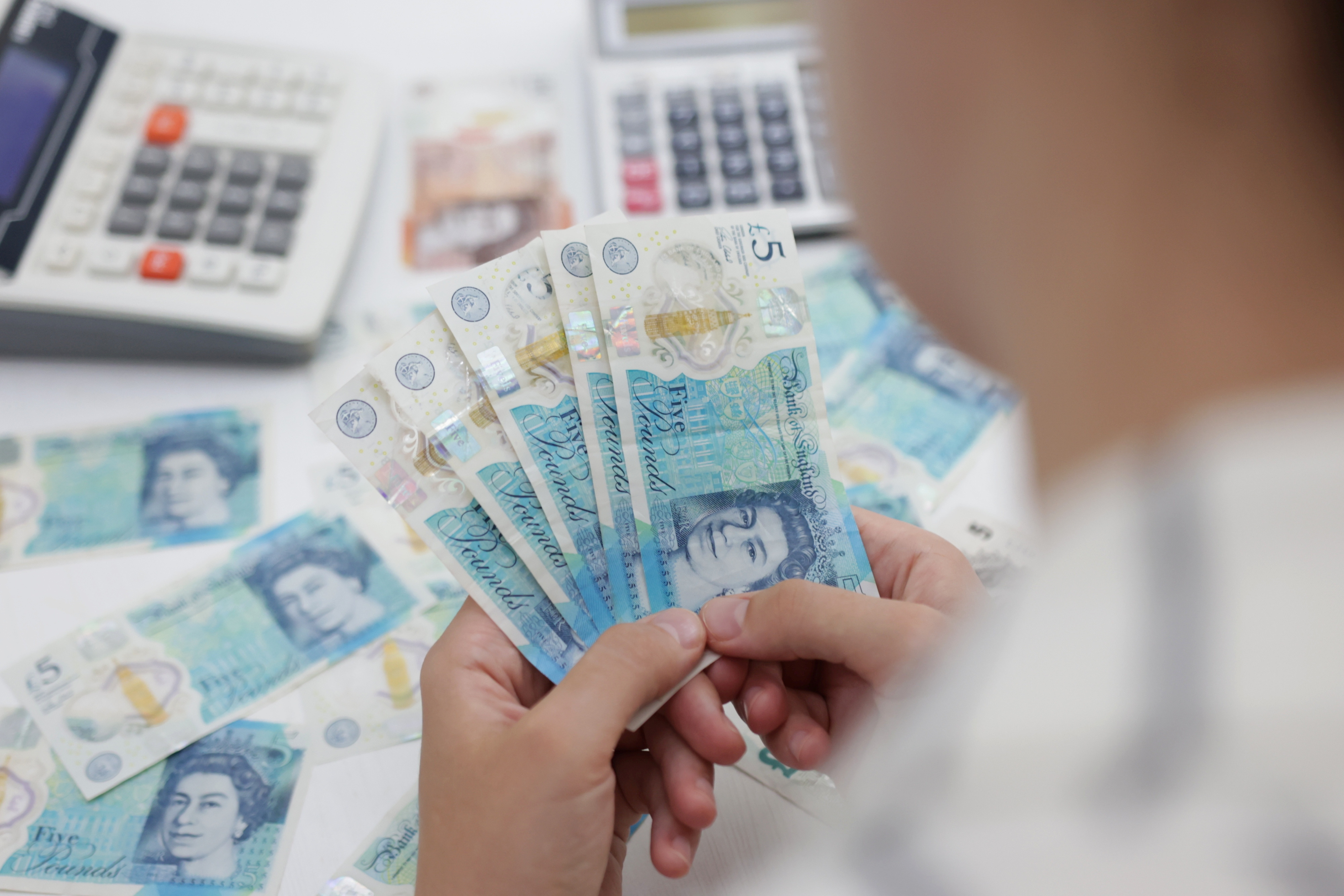 A woman holds British pound banknotes in this illustration taken May 30, 2022.