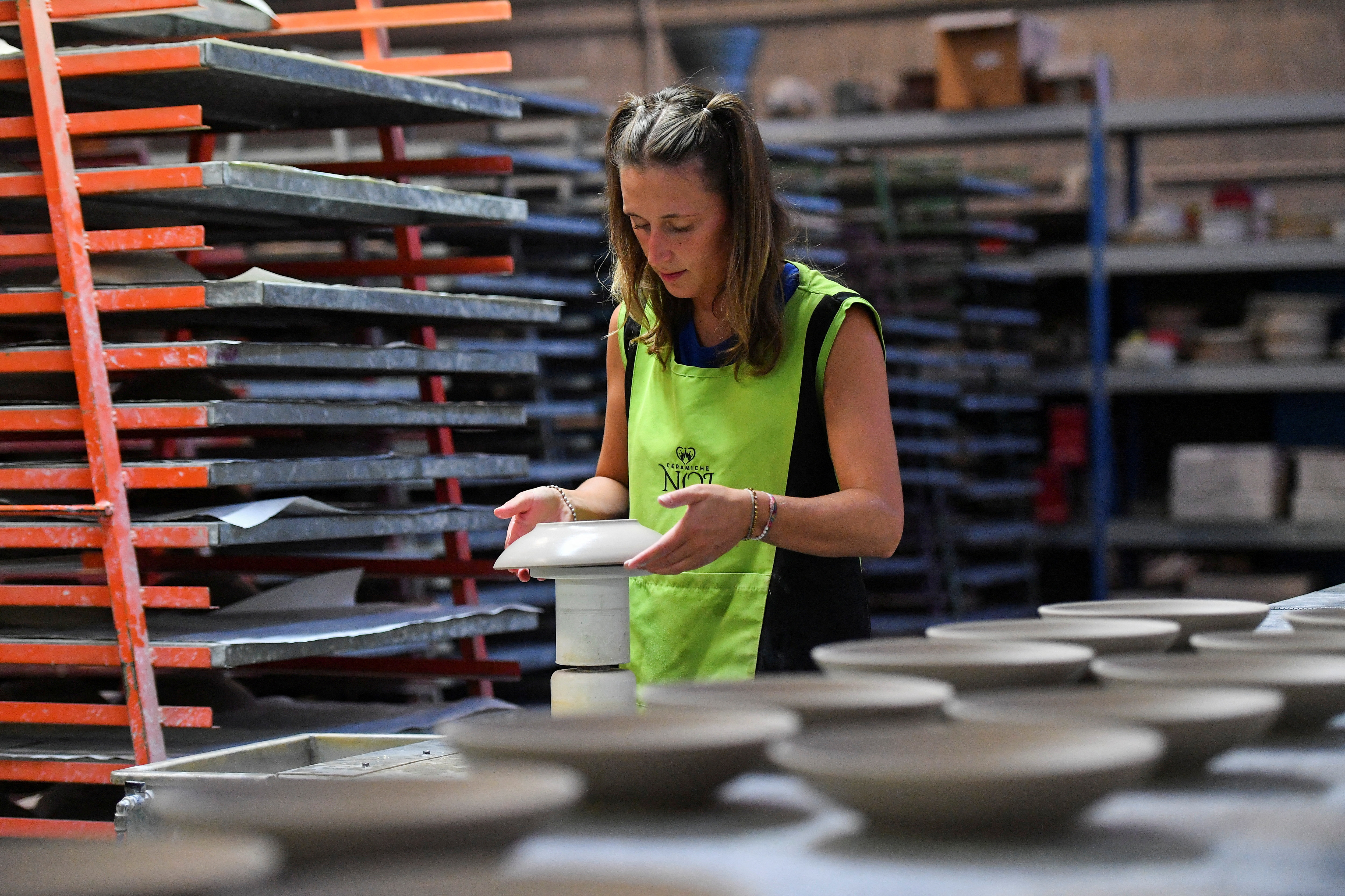 An employee works at a ceramics factory where the workers start their shifts before dawn to optimize sunlight and save energy, in Citta di Castello, Italy, Aug. 30, 2022.