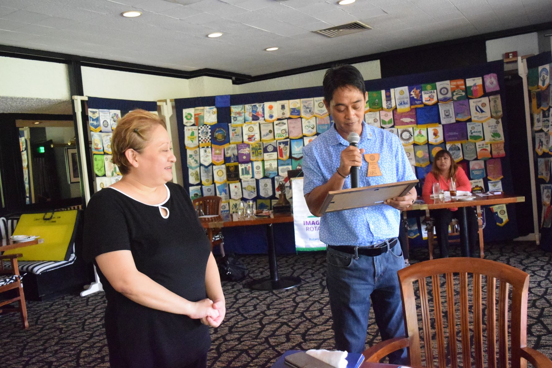 Public School System Career & Technical Education Program Director Jessica B. Taylor, left, looks on as Rotary Club of Saipan President Wendell Posadas reads a certificate of appreciation during the club's luncheon meeting on Tuesday at the Hyatt Regency Saipan's Giovanni's Restaurant.