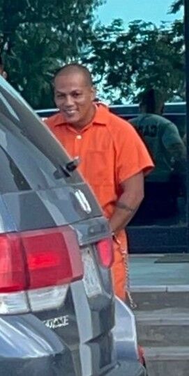 Dennis Sanchez Reyes smiles as he is escorted out of the Guma Hustisia by a Corrections officer after a bail hearing on Tuesday afternoon.