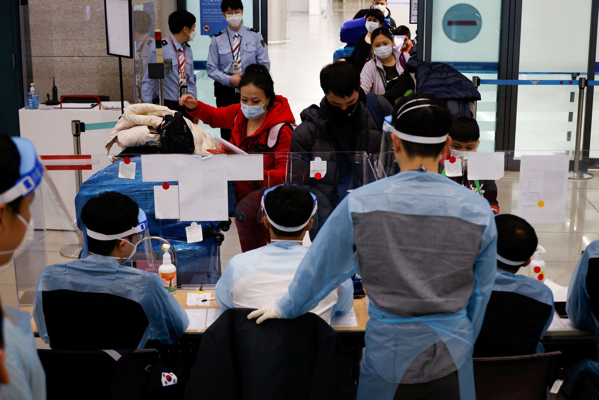 Workers wearing protective gear check passengers from overseas as they arrive at the Incheon International Airport, amid the coronavirus disease pandemic in Incheon, South Korea, Dec. 28, 2020.