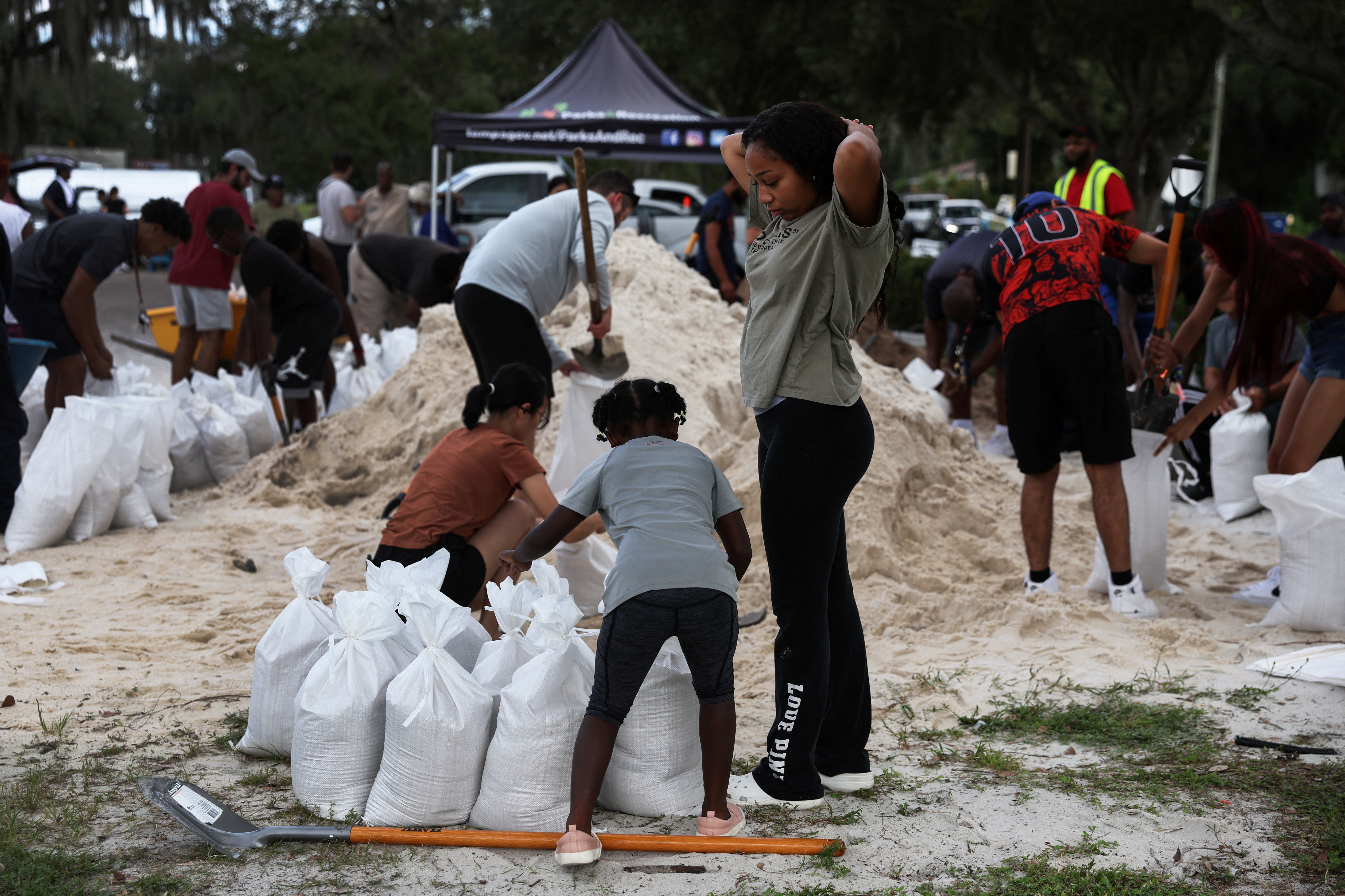 Alicia Dhall, 18, looks down as her sister Ariana, 8, and local residents fill sandbags, as Hurricane Ian spun toward Florida carrying high winds, torrential rains and a powerful storm surge, at the Al Barnes Park in Tampa, Florida, Sept. 26, 2022.