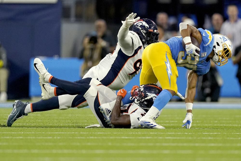Los Angeles Chargers running back Austin Ekeler, right, is hit by Denver Broncos cornerback Damarri Mathis, center, during the first half of an NFL football game, Monday, Oct. 17, 2022, in Inglewood, Calif.