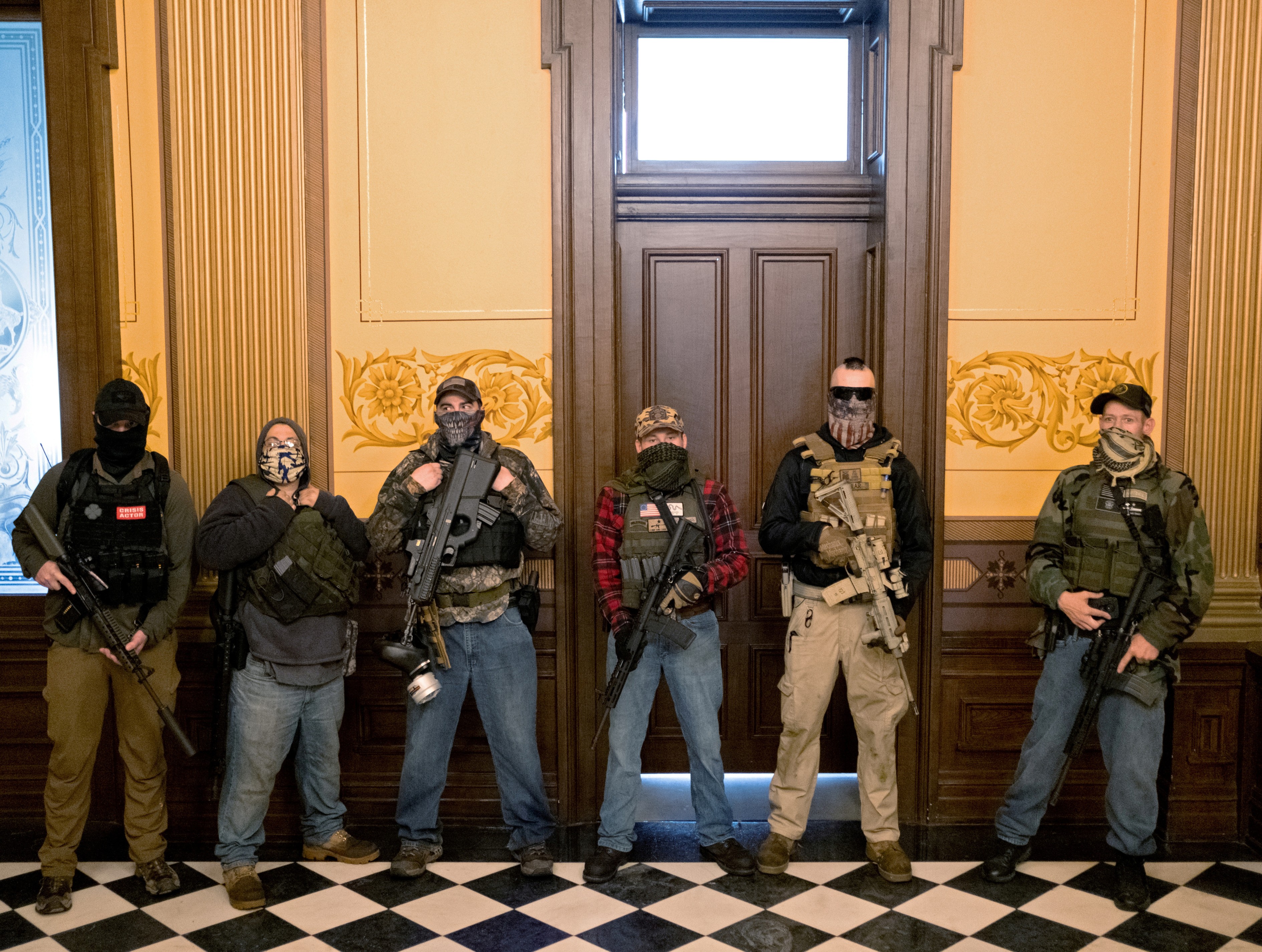 A militia group with no political affiliation from Michigan, including Joseph Morrison, 3rd right, Paul Bellar, 2nd right, and Pete Musico, right, who were charged for their involvement in a plot to kidnap Michigan Gov. Gretchen Whitmer, attack the state capitol building and incite violence, stand in front of the governor's office after protesters occupied the state capitol during a vote to approve the extension of Whitmer's emergency declaration/stay-at-home order due to the coronavirus disease outbreak, in Lansing, Michigan, April 30, 2020.