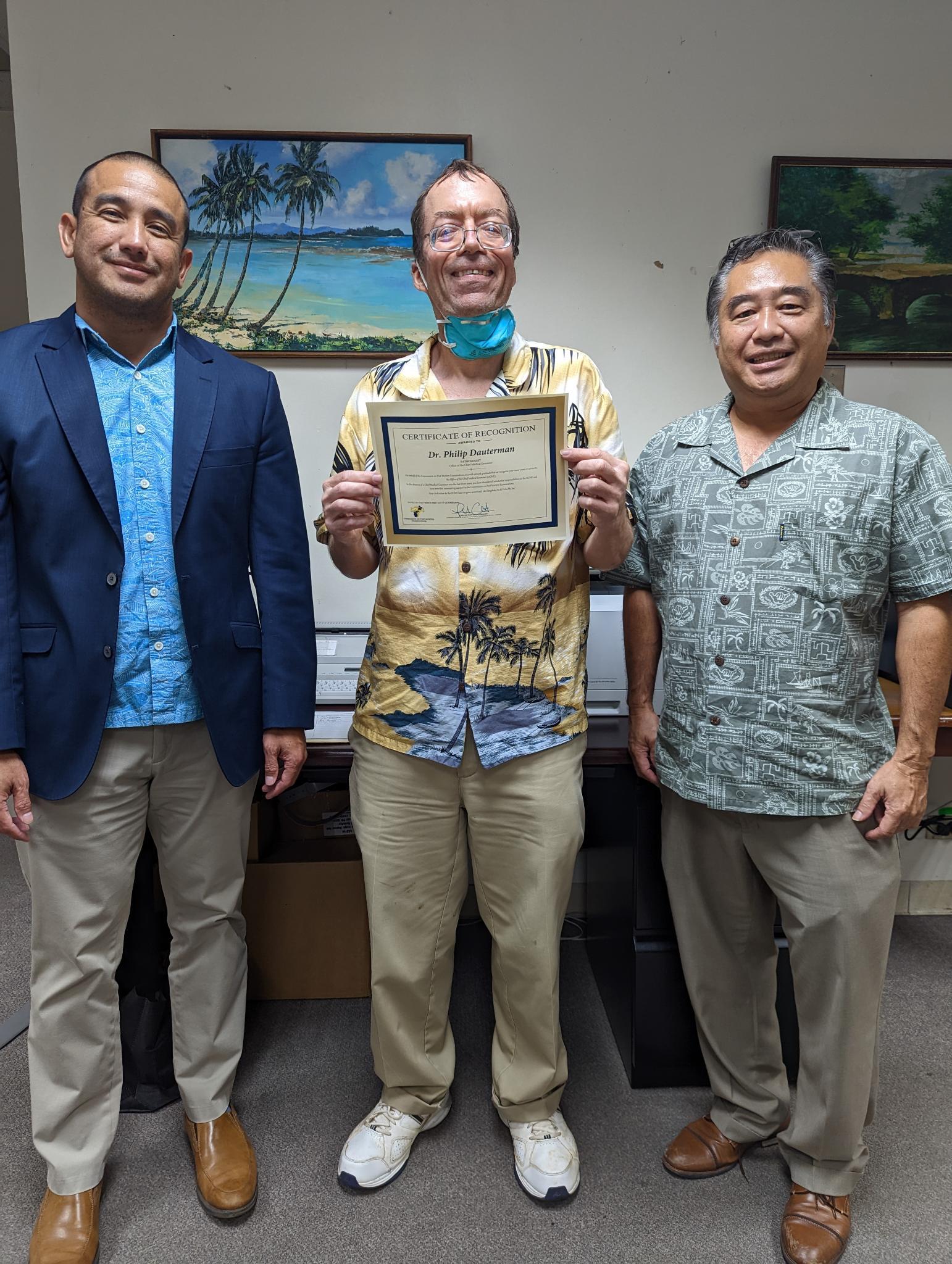 Dr. Philip Dauterman, center, receives a certificate of recognition from Guam Attorney General Leevin Camacho, left.